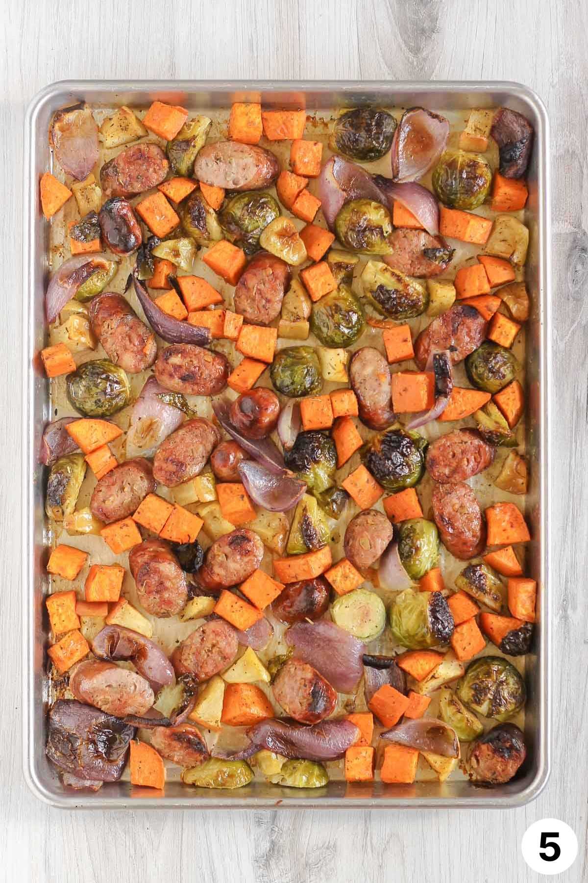 Roasted vegetables, apples, and chicken sausage on a large baking sheet.