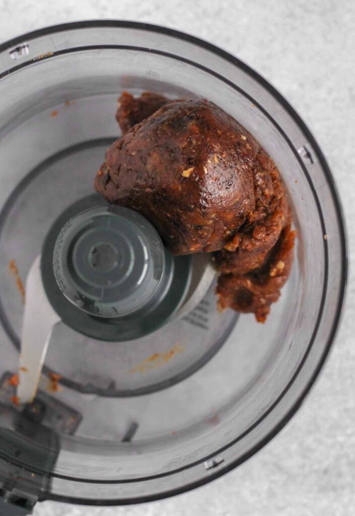 Large ball of blended dates in a food processor.