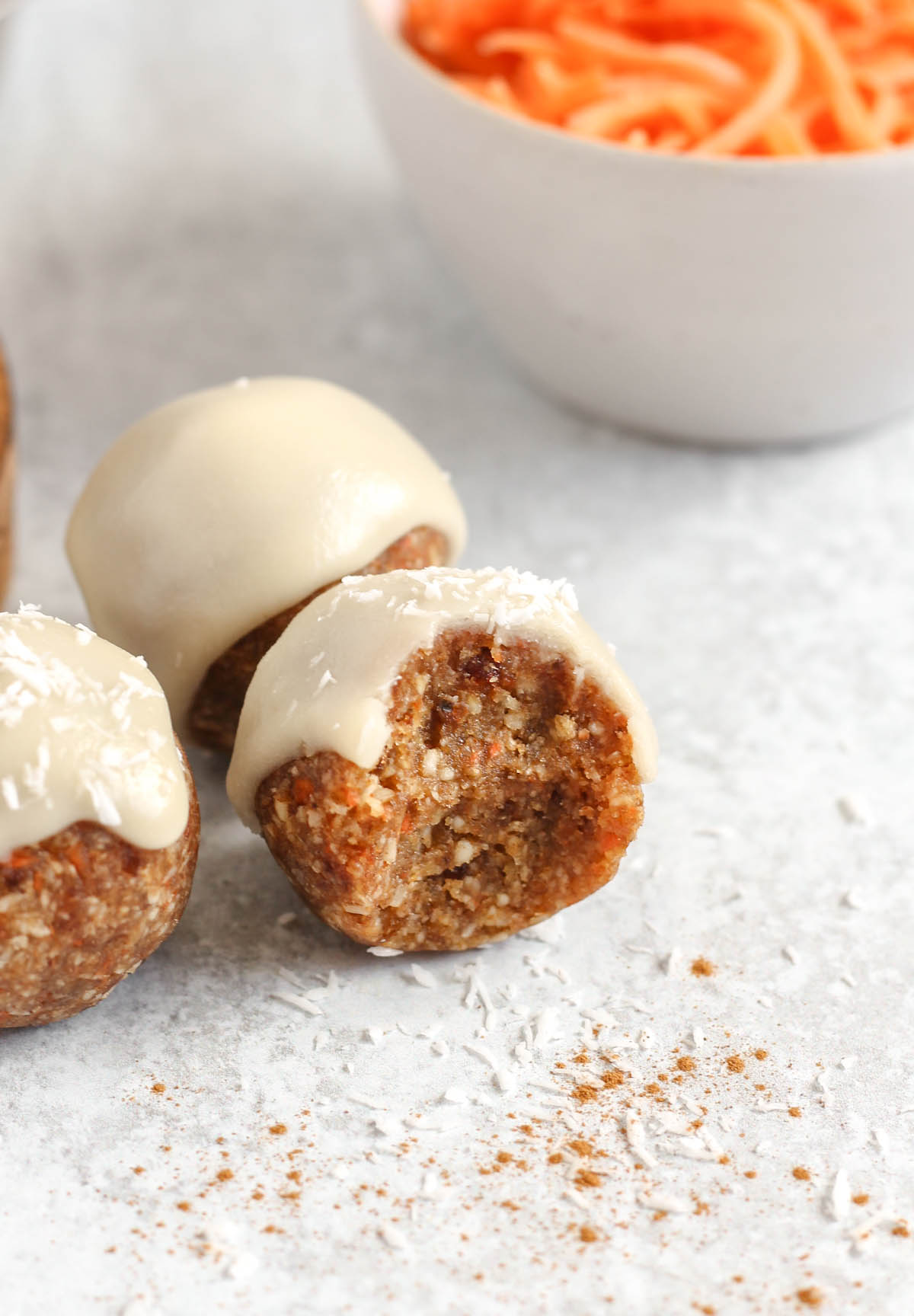 A carrot cake ball with a bit taken out to show texture with 2 balls behind.