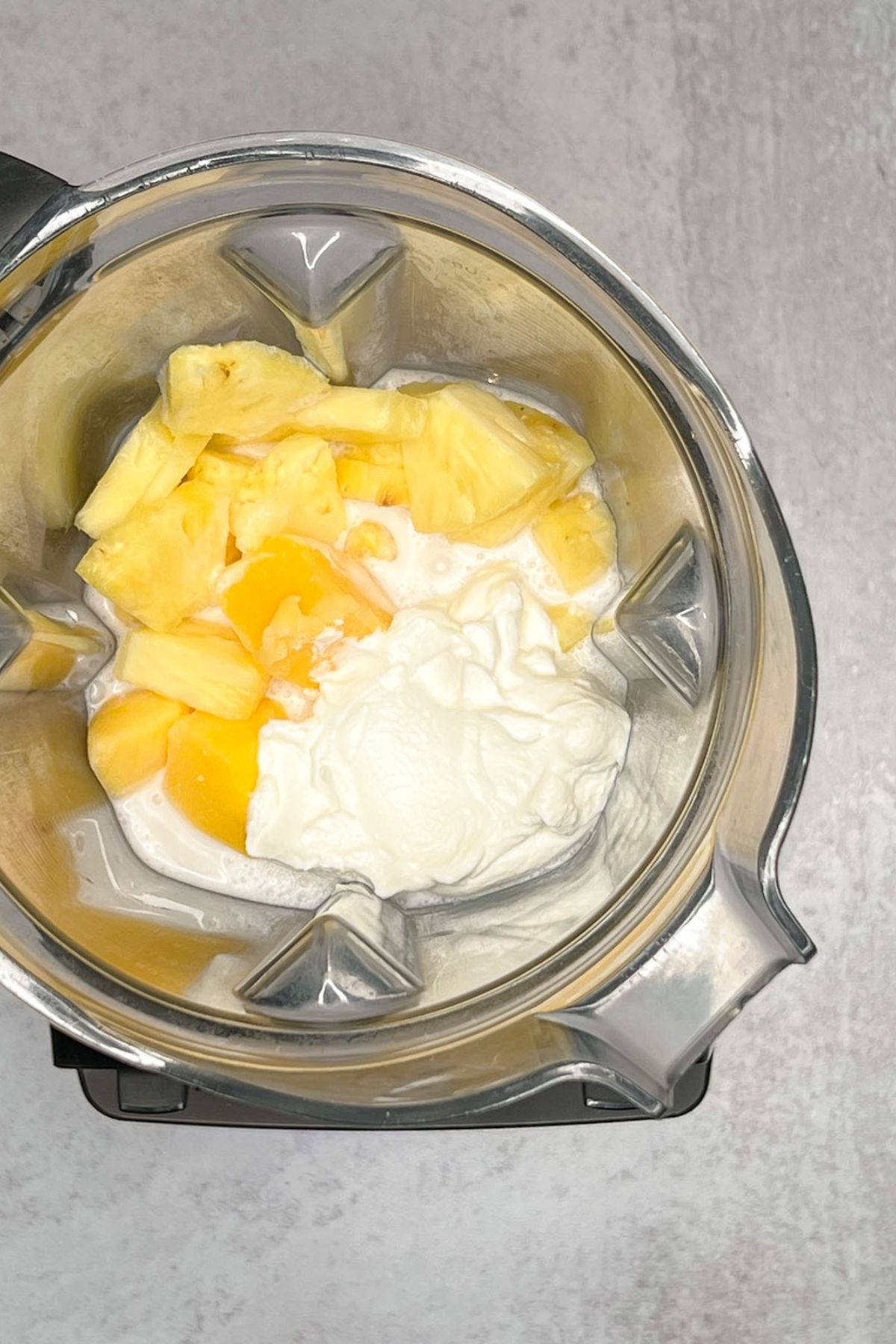 Yogurt, milk, mango, and pineapple in a blender.