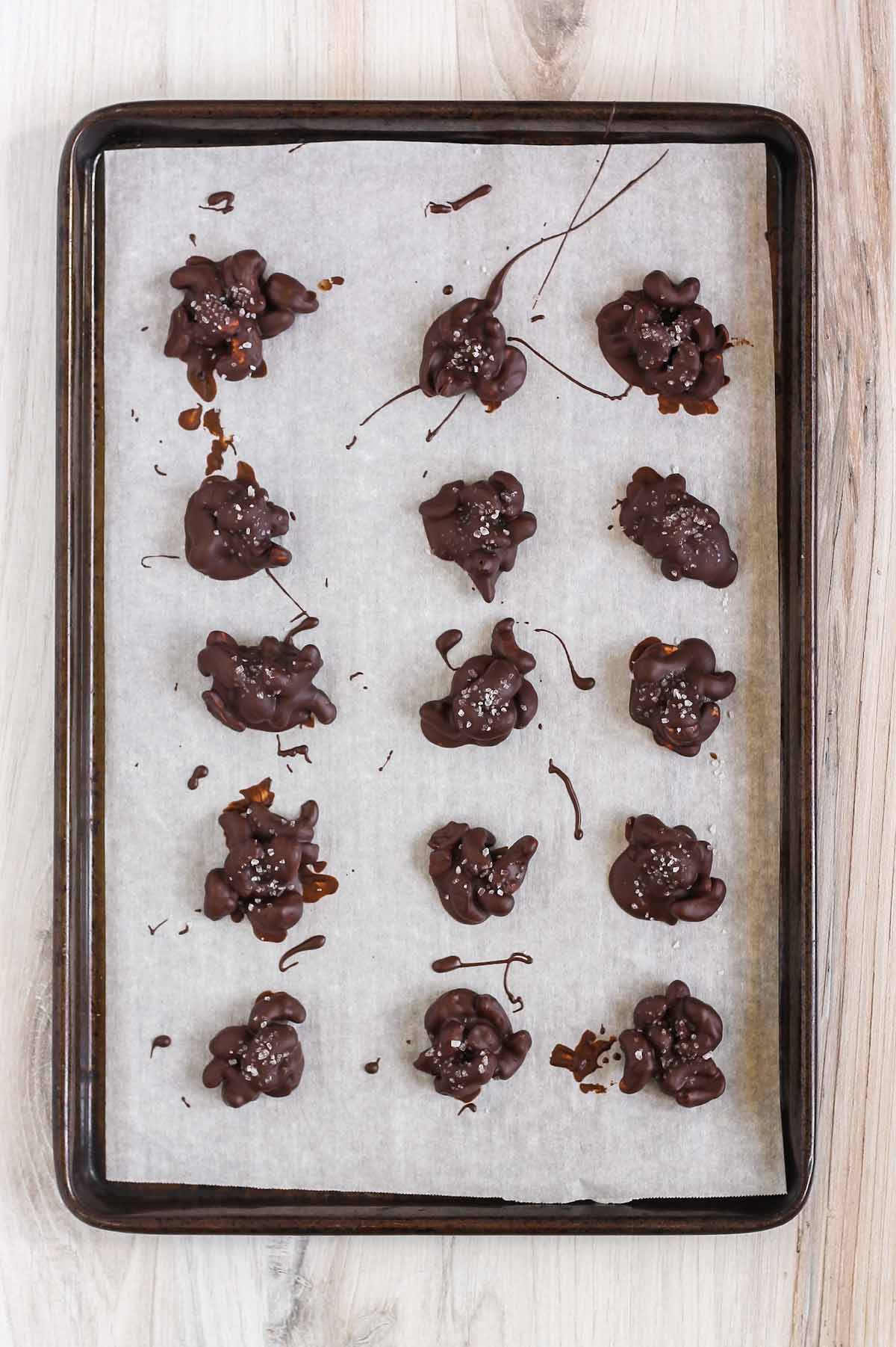 Chocolate cashew clusters on a baking sheet lined with parchment paper.