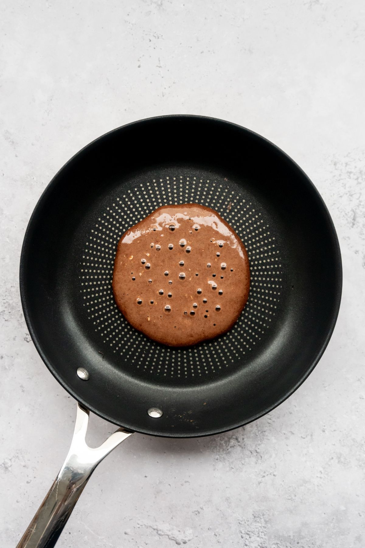Chocolate pancake batter on a frying pan.