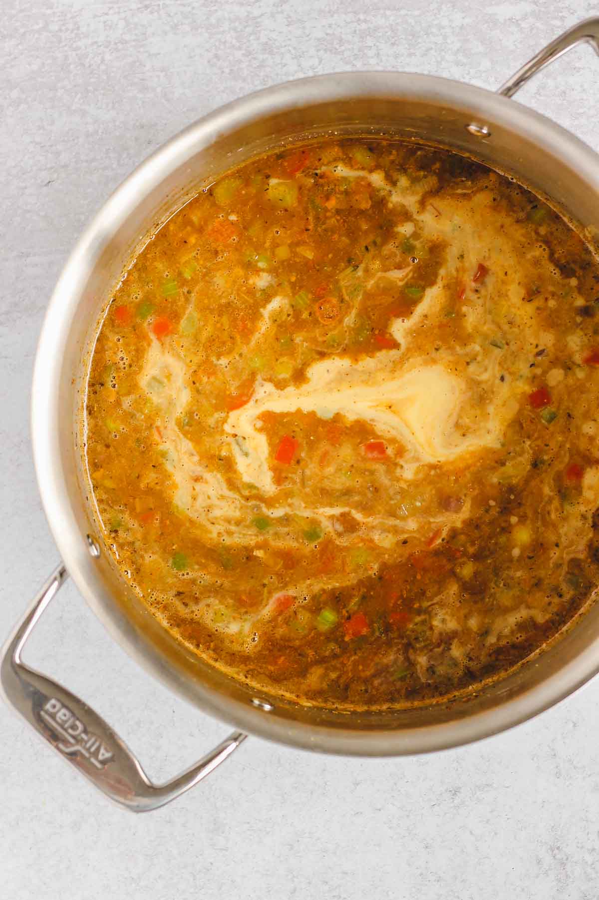 Base of chicken chili in a stainless steel pot with pureed corn being mixed in.