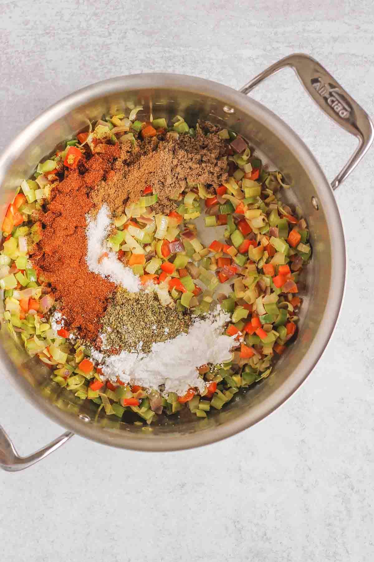 Sauteed veggies and seasonings in a large stainless steel stock pot.