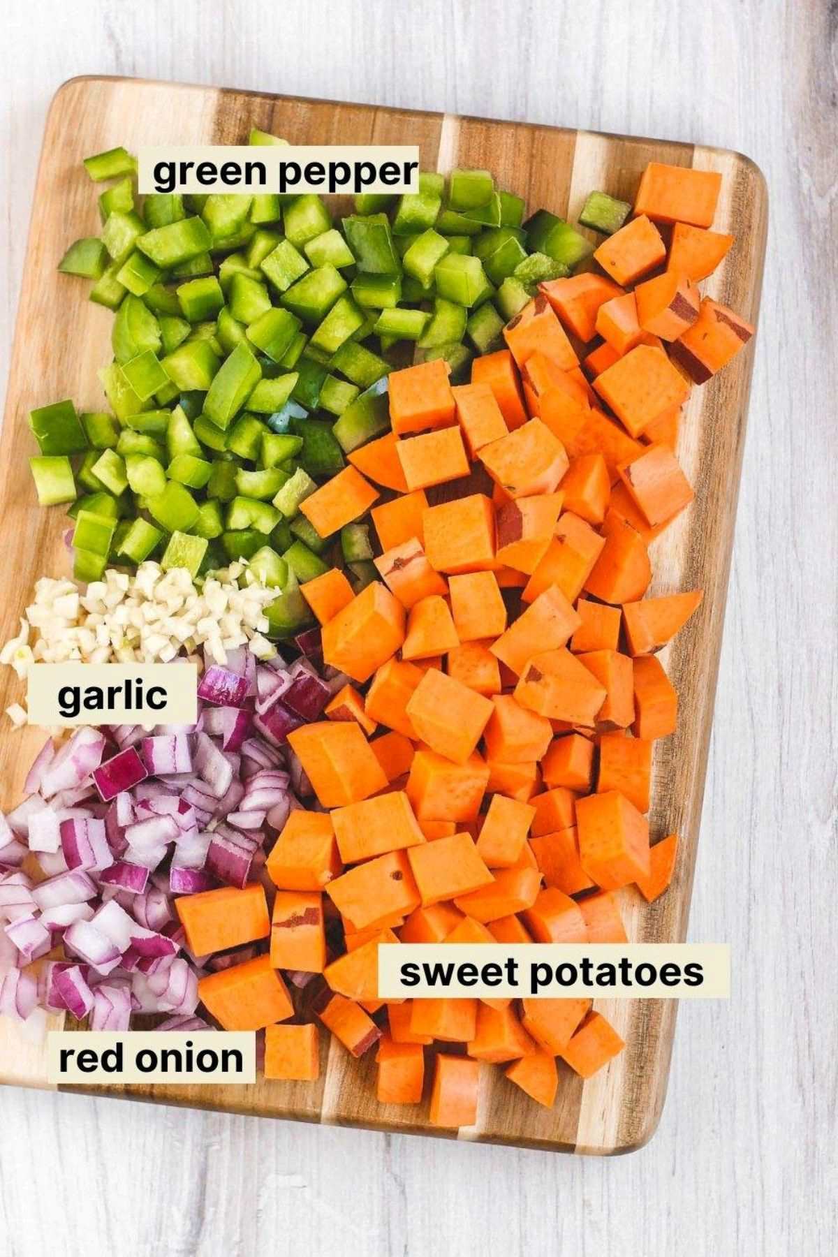Chopped veggies and garlic on a cutting board with labels next to each food item.