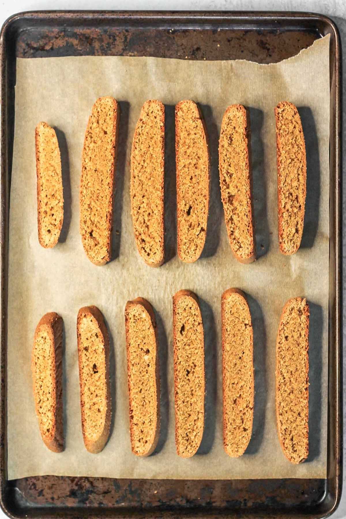 Sliced biscotti on a parchment paper lined baking sheet after baking the first time.