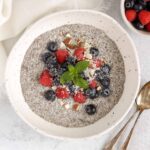 Chia bowl topped with fresh blueberries, raspberries, and chopped almonds with two vintage spoons in the bowl.