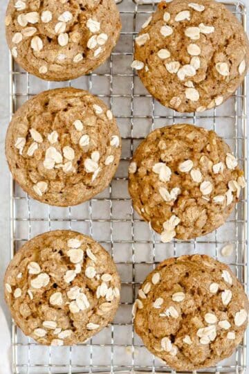 Apple cinnamon oat muffins on a wire cooling rack.