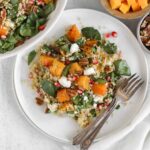 Single serving of fall quinoa salad with roasted butternut squash on a small white plate with 2 vintage forks.