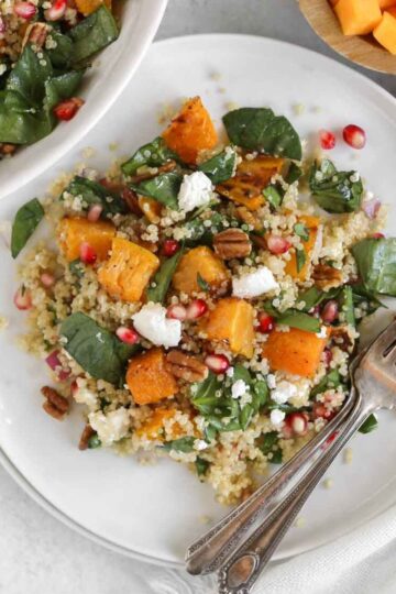Single serving of fall quinoa salad with roasted butternut squash on a small white plate with 2 vintage forks.