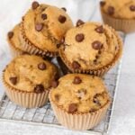 Stacked banana protein muffins with chocolate chips on a small rectangular wire colling rack.