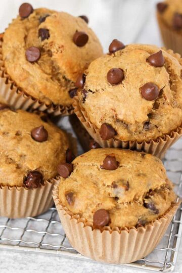 Stacked banana protein muffins with chocolate chips on a small rectangular wire colling rack.