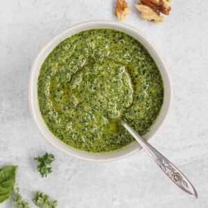 Pesto in a small bowl with a spoon in the pesto.