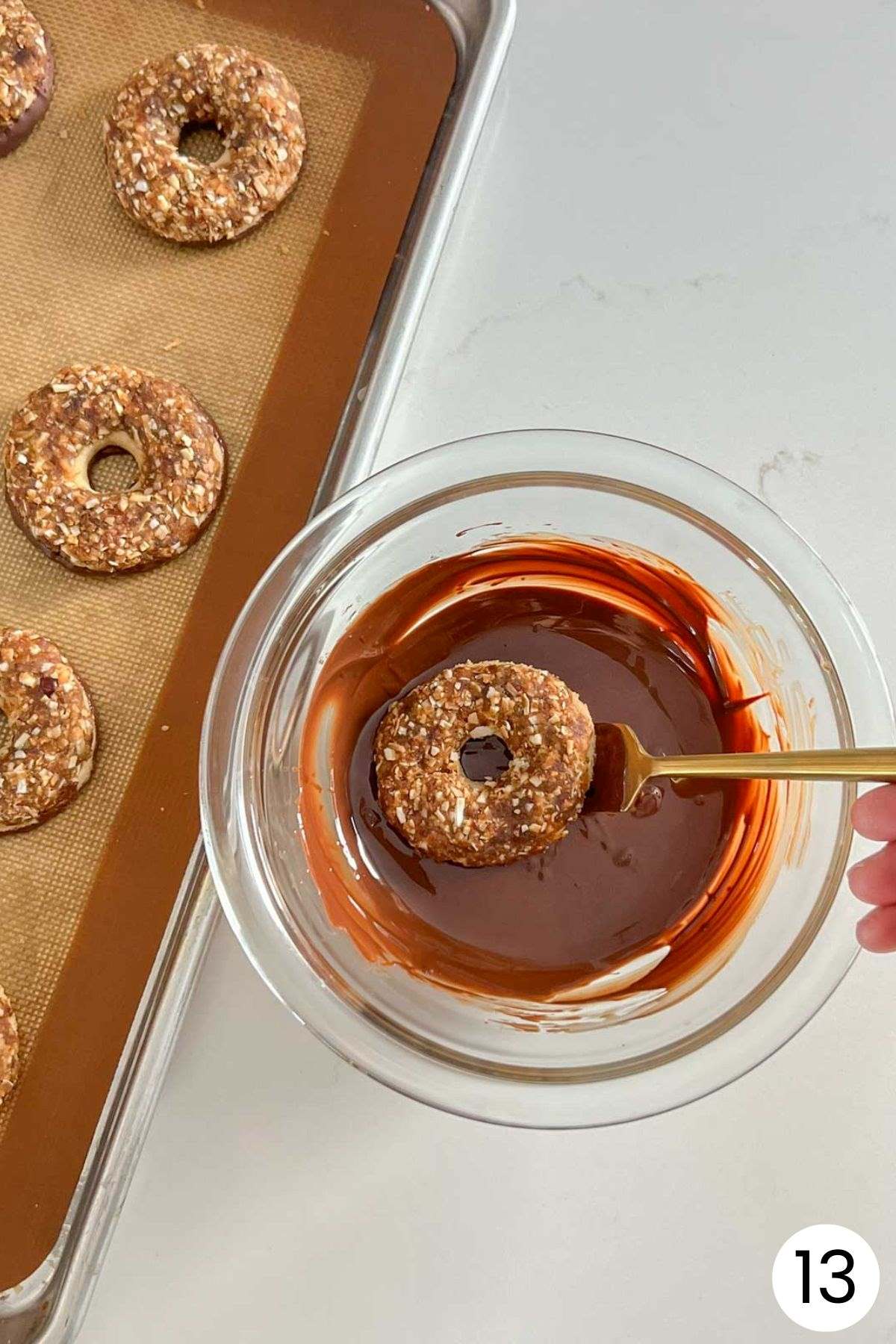 Single Samoa cookie being dipped in melted chocolate with a fork with the number 13 in the bottom corner.