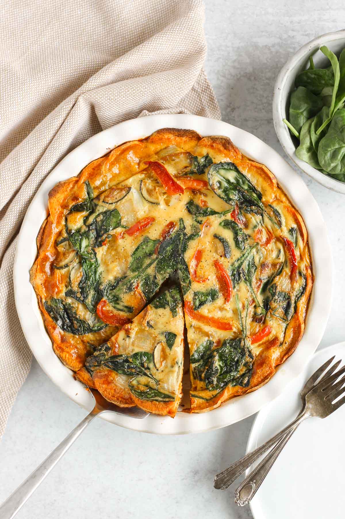 Sweet potato crust quiche with one slice cut and being served from the pie dish.