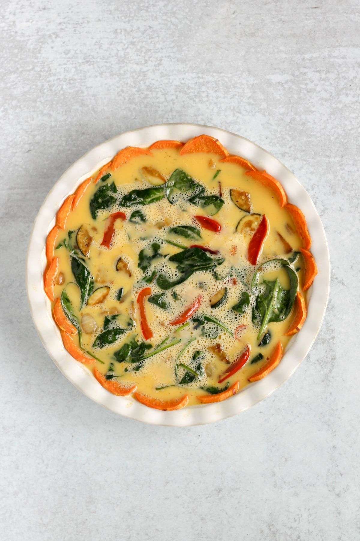 Sweet potato crust quiche in a pie dish uncooked.