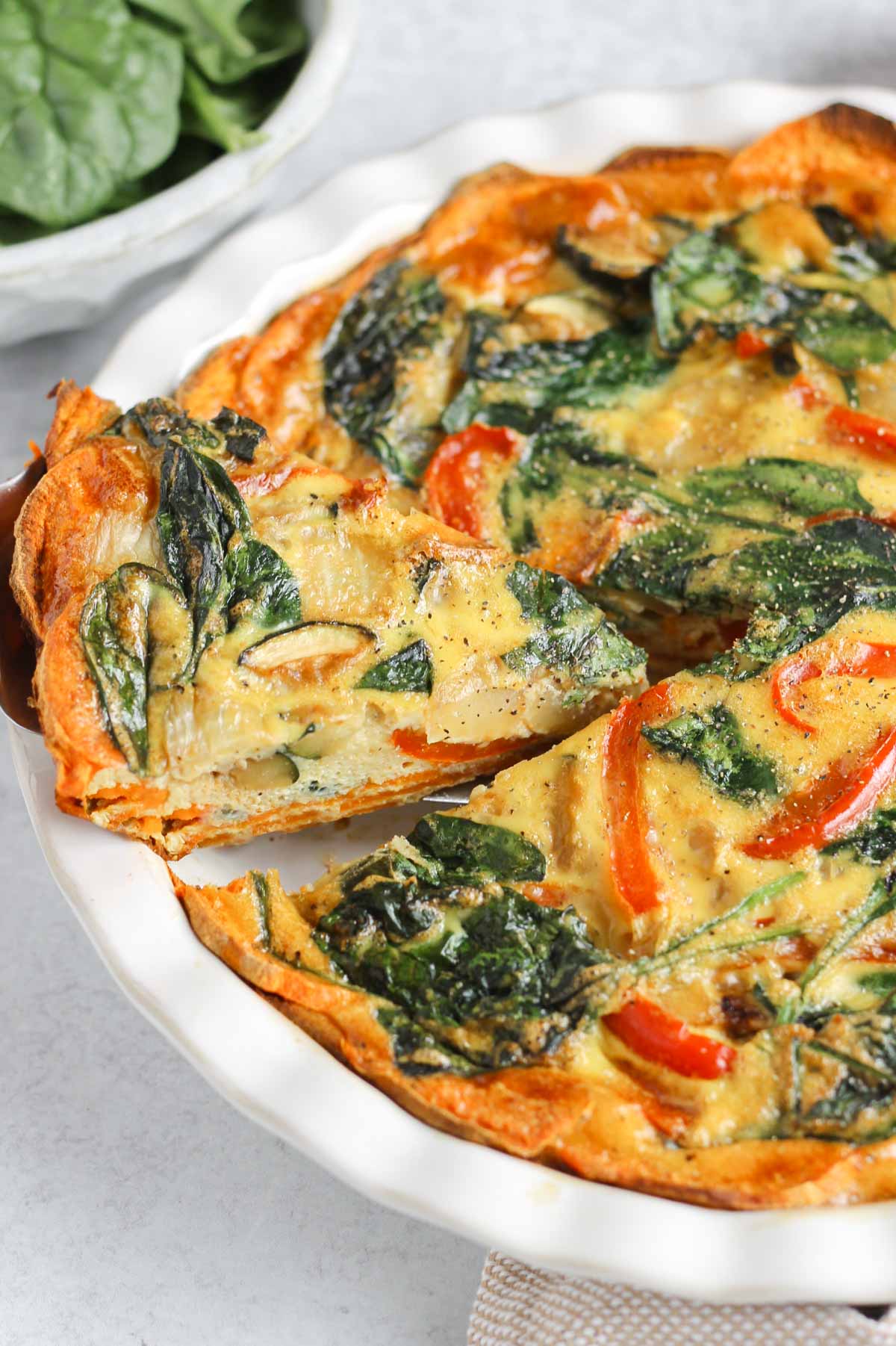 Slice of sweet potato crust quiche being pulled from a pie dish.