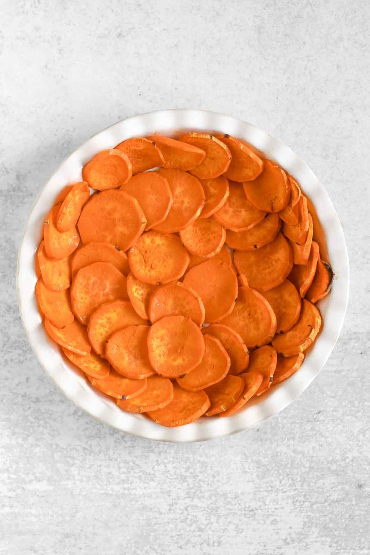 Baked sweet potato slices in a white pie plate.