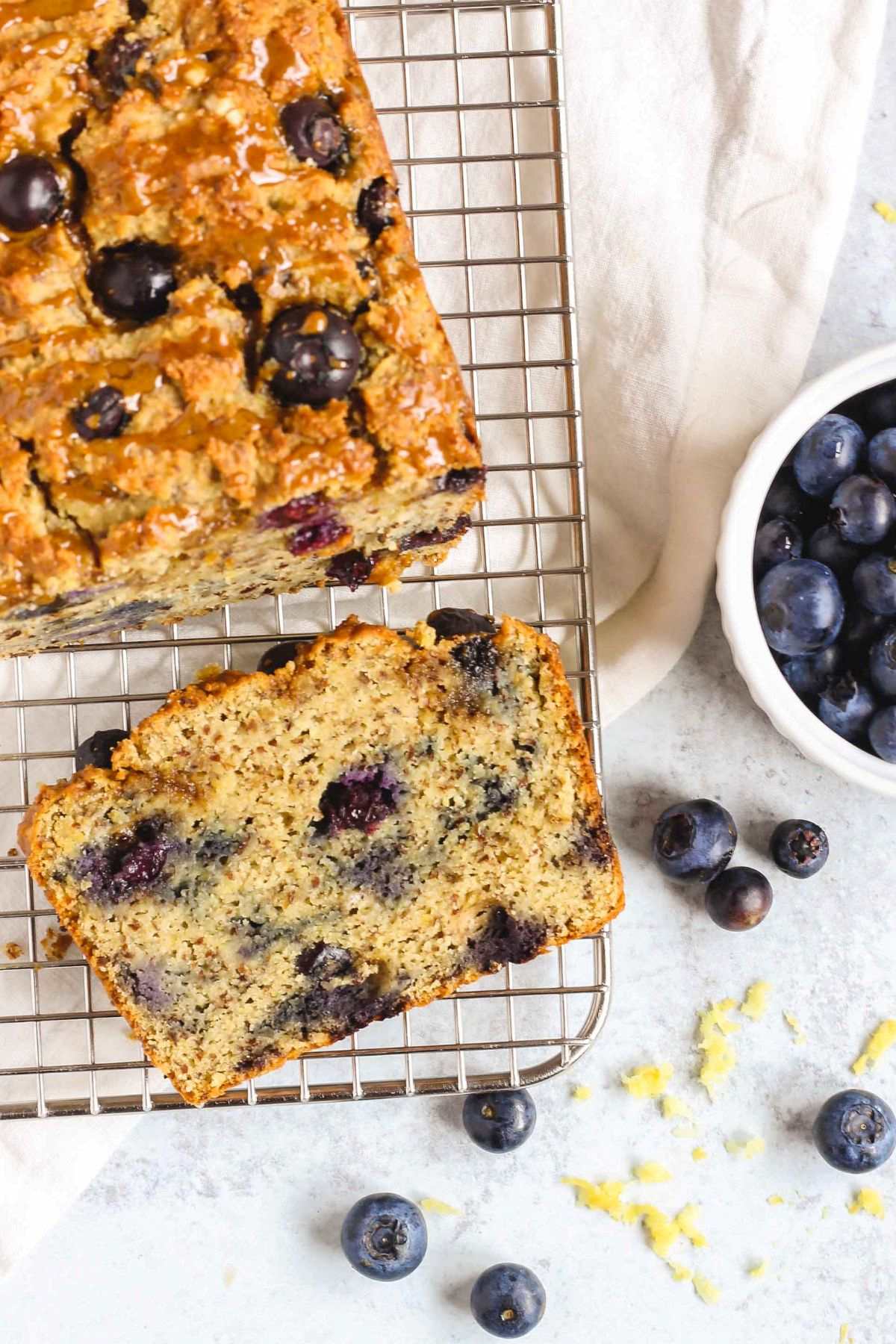 Blueberry lemon almond flour bread with one slice cut from the loaf on a wire cooling rack.