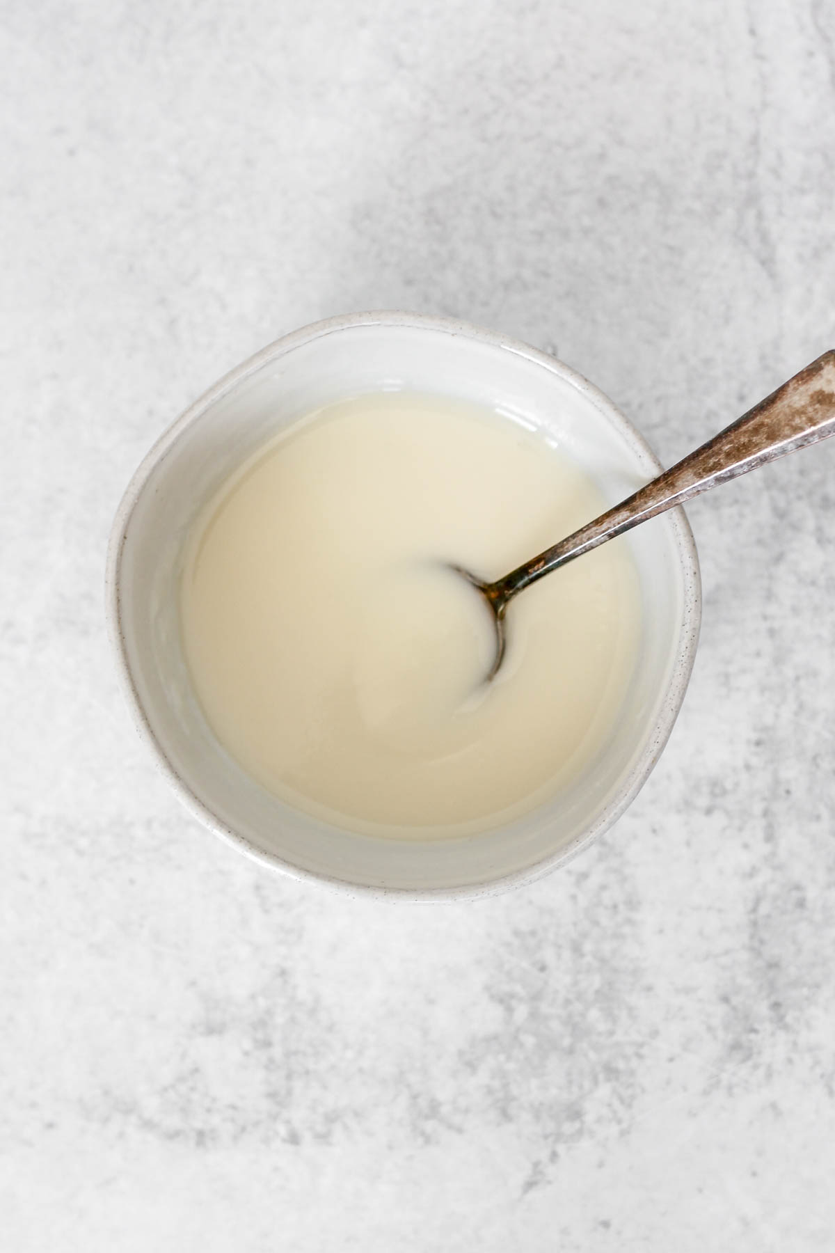 Coconut butter icing with a vintage spoon in a small ceramic bowl.