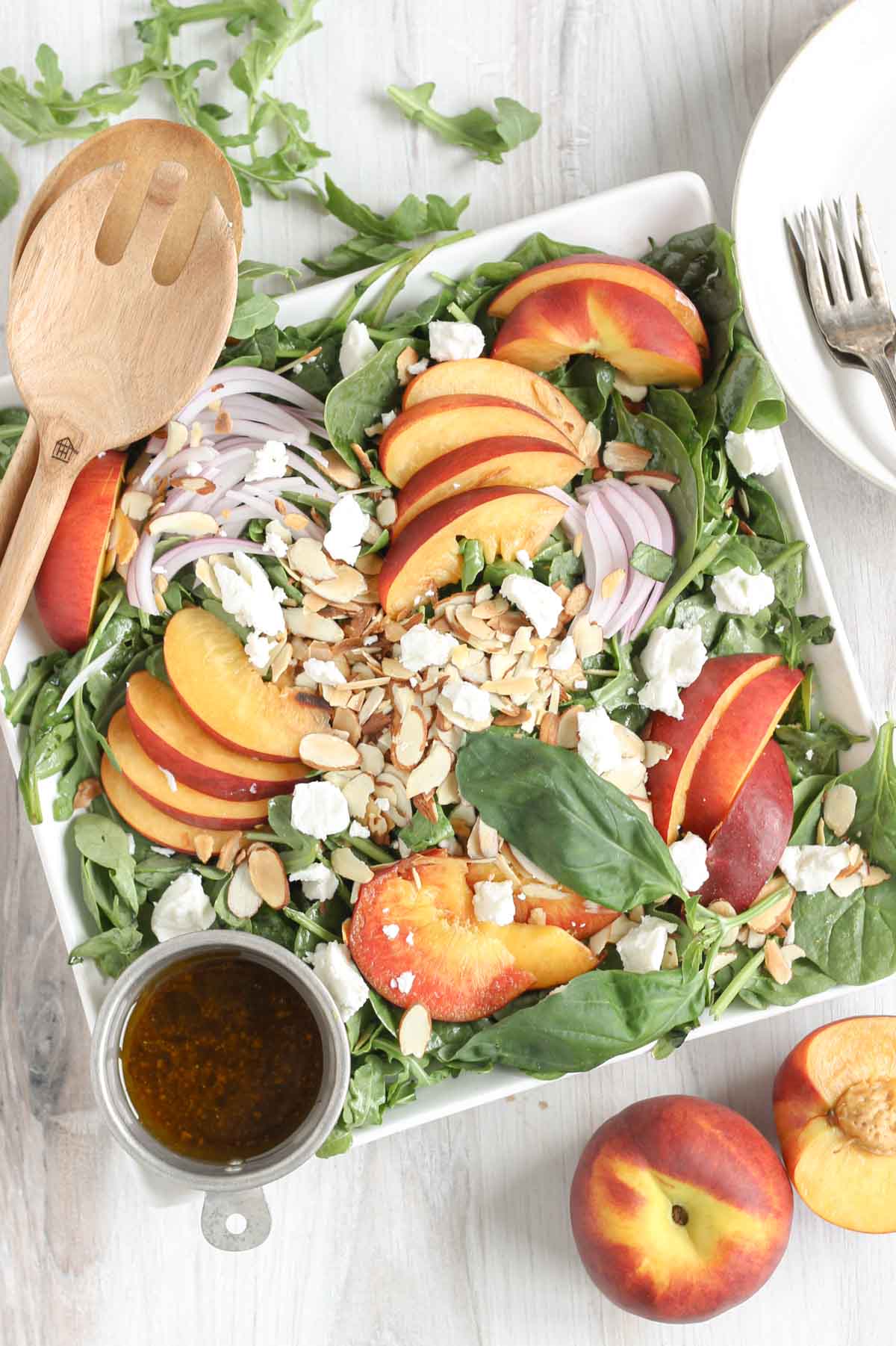 Peach and goat cheese salad with a side of balsamic vinaigrette and sliced peaches on the side.