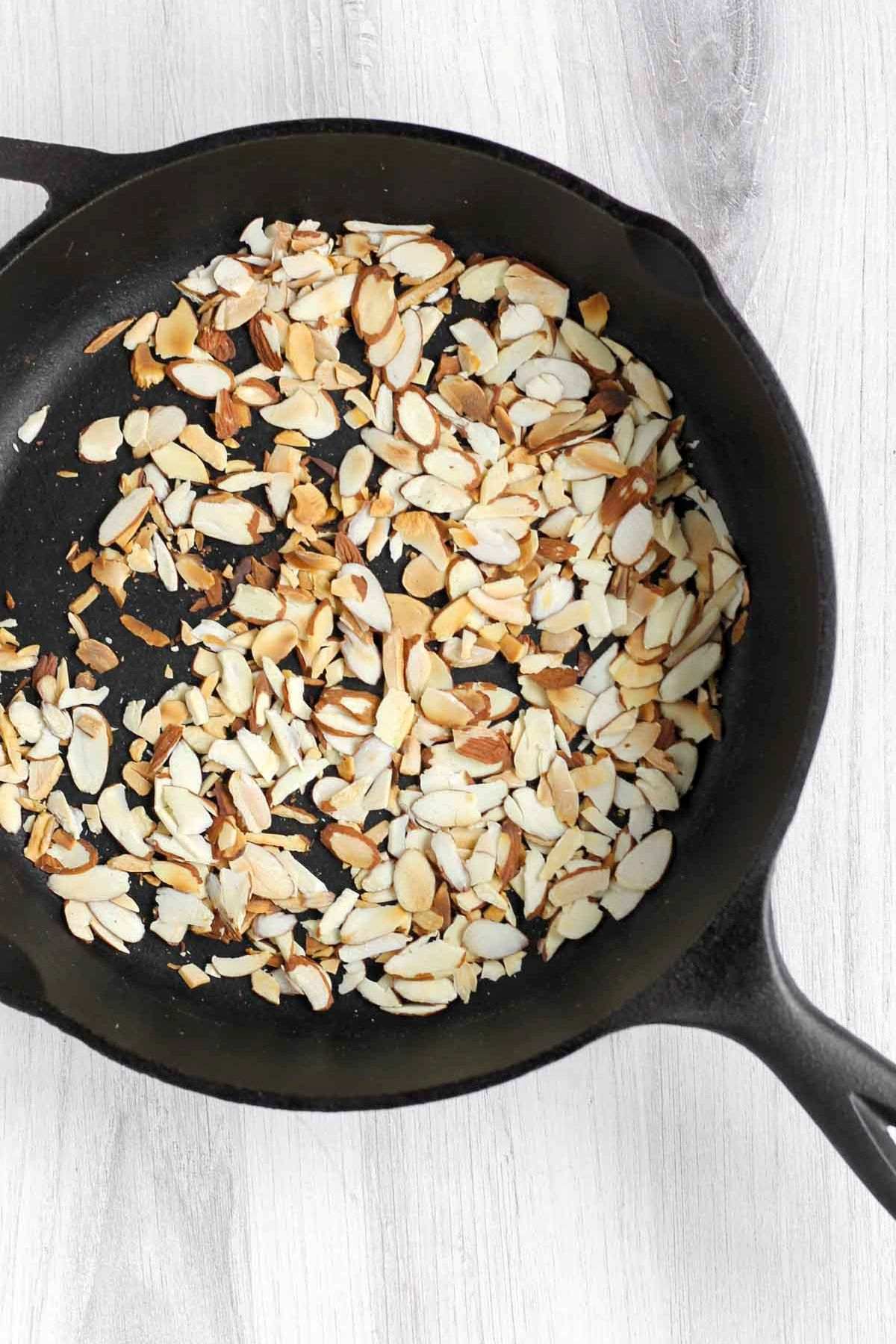 Toasted sliced almonds in a cast iron skillet.