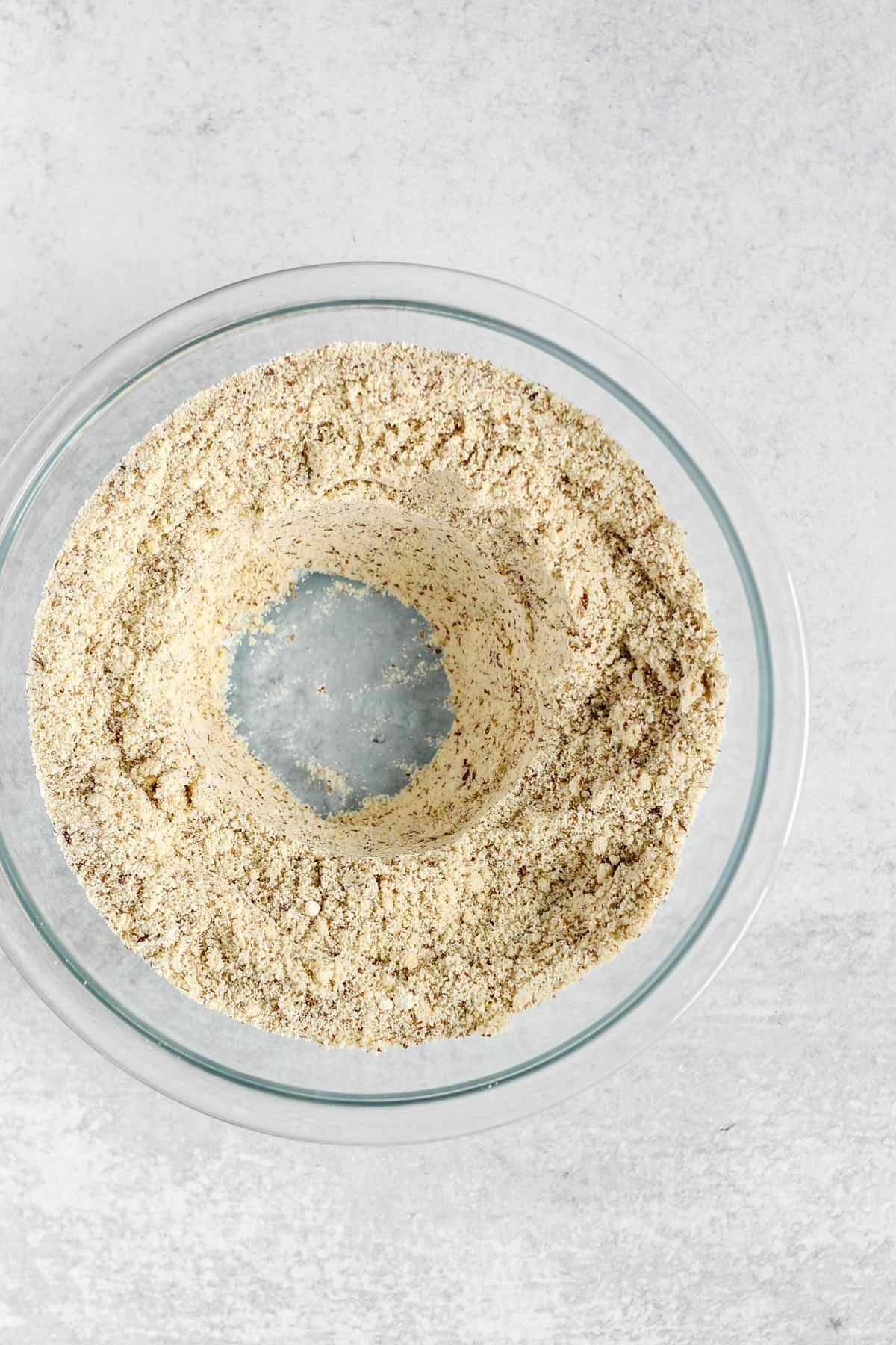 Dry ingredients for almond flour bread, with a well in the center, in a glass mixing bowl.