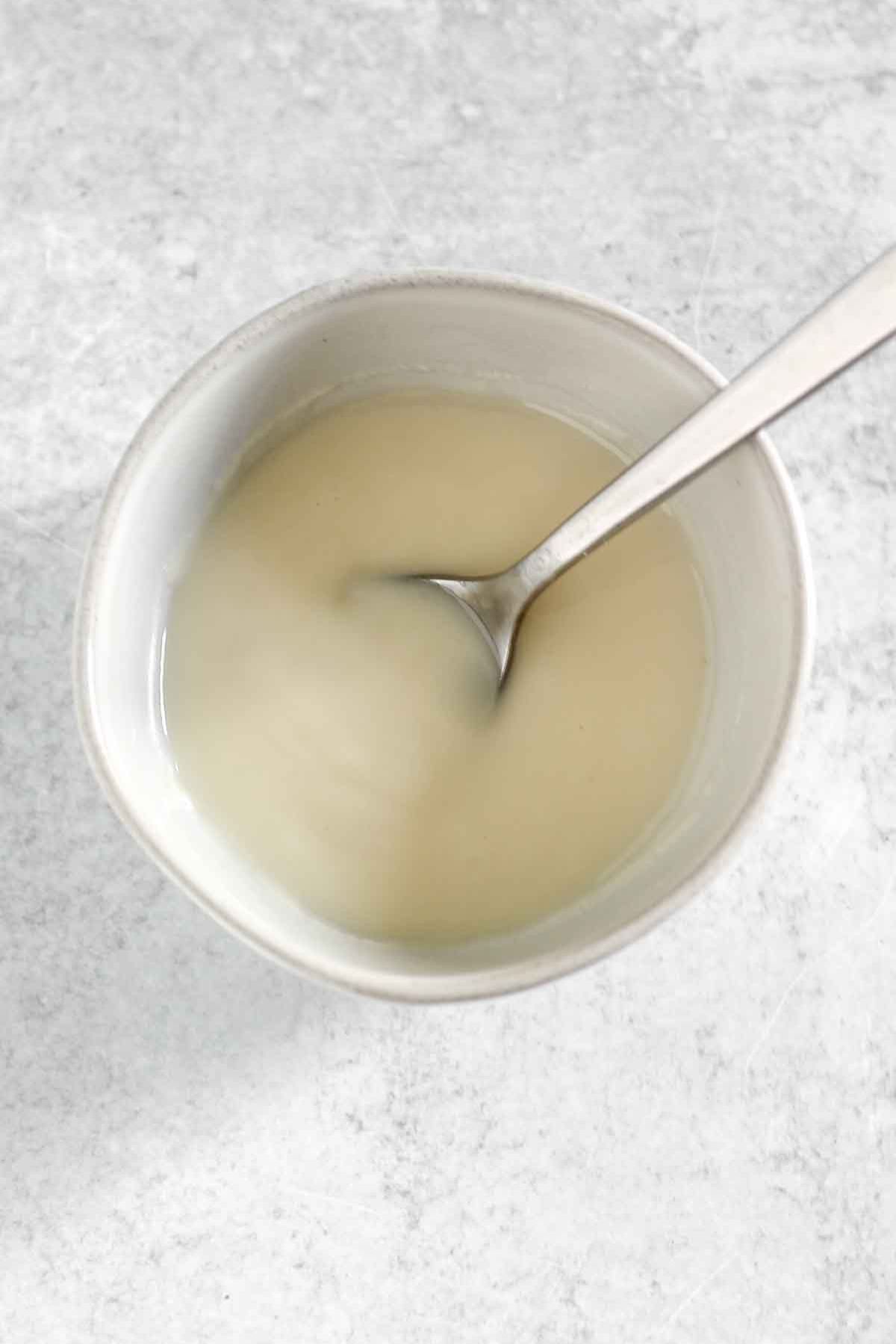 Melted coconut butter in a small bowl with a spoon.