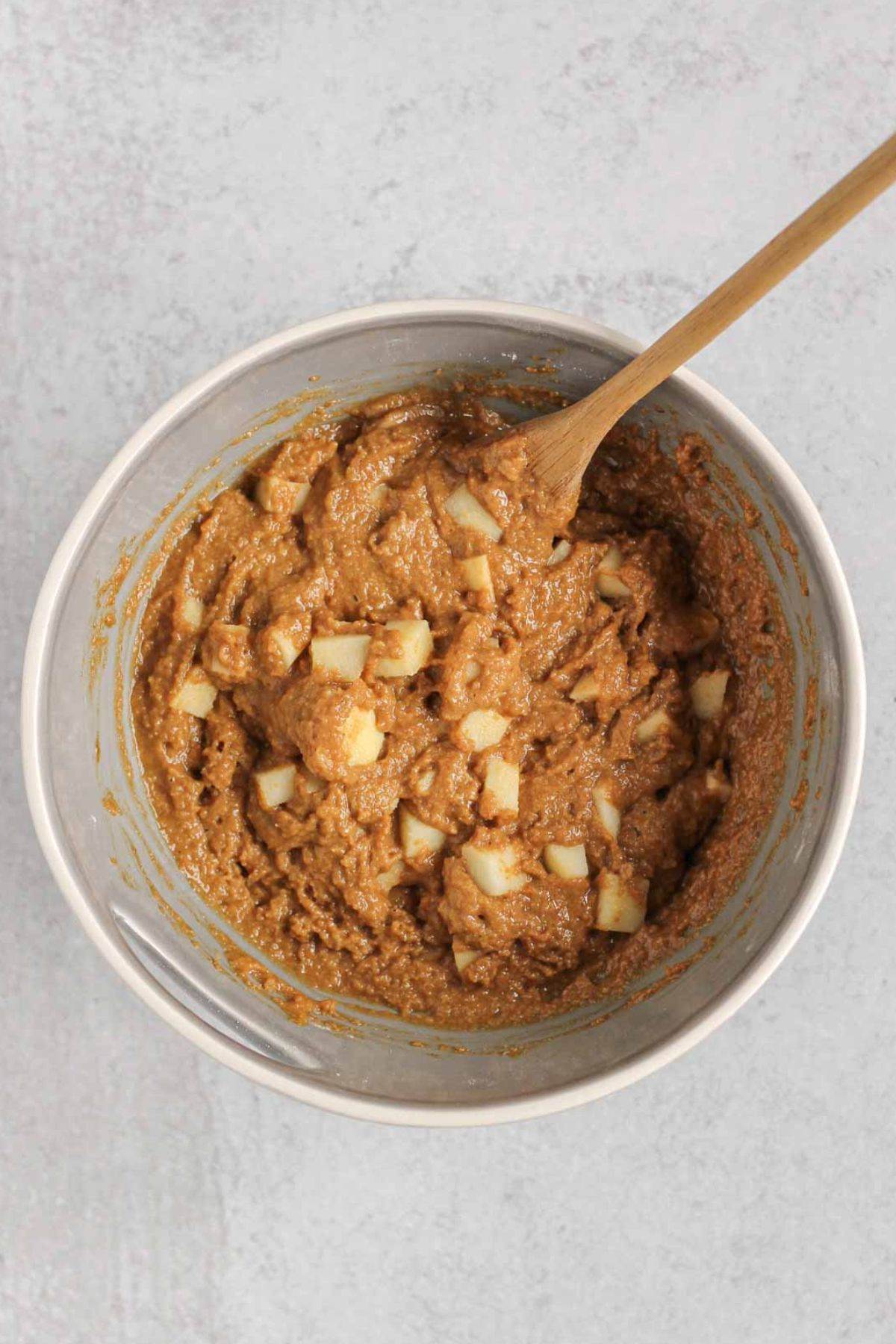 Mixing bowl with apples being folded into apple bread batter.