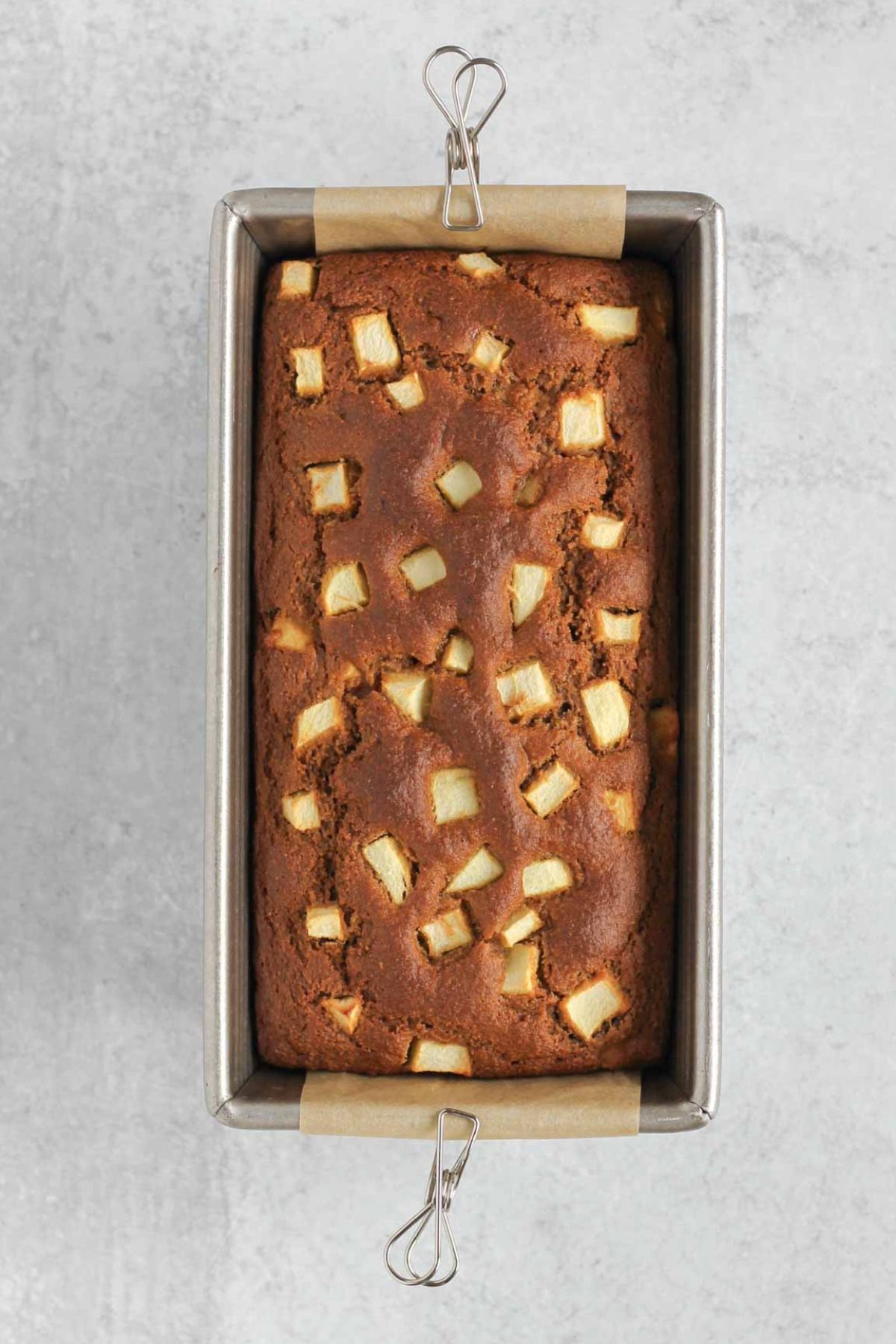 Baked loaf of apple bread in a loaf pan.