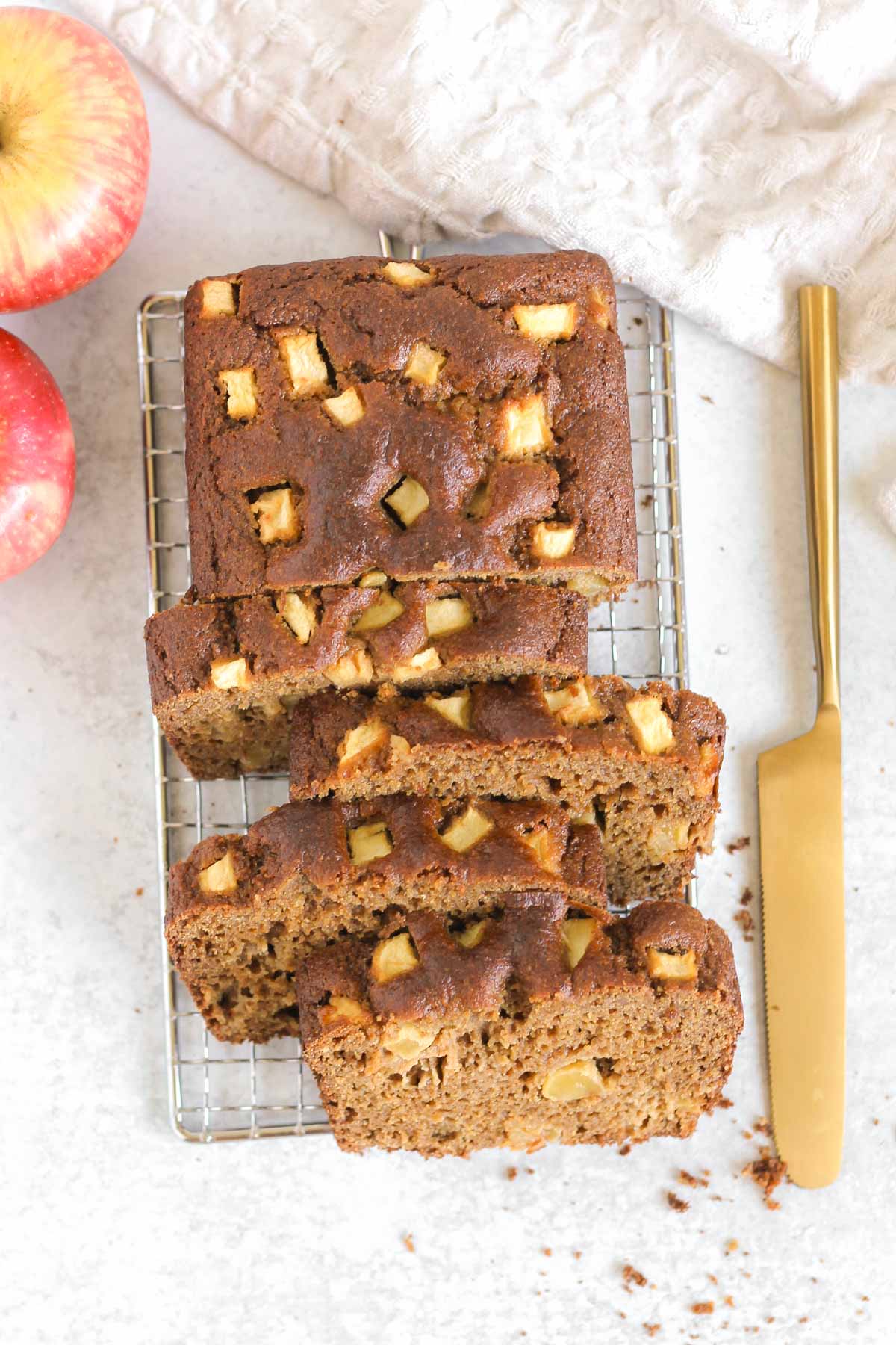 Half sliced loaf of apple bread on a wire cooling rack.