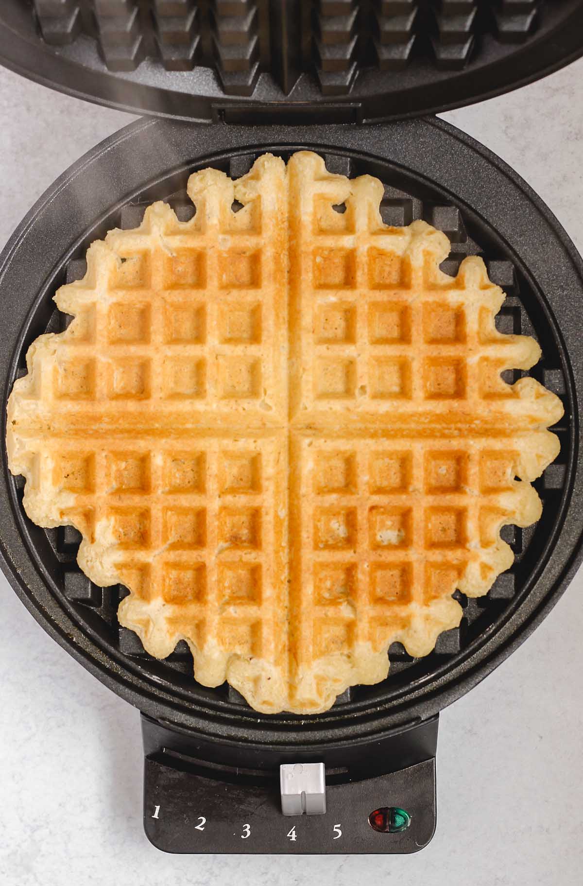 Cooked waffle in a waffle iron.
