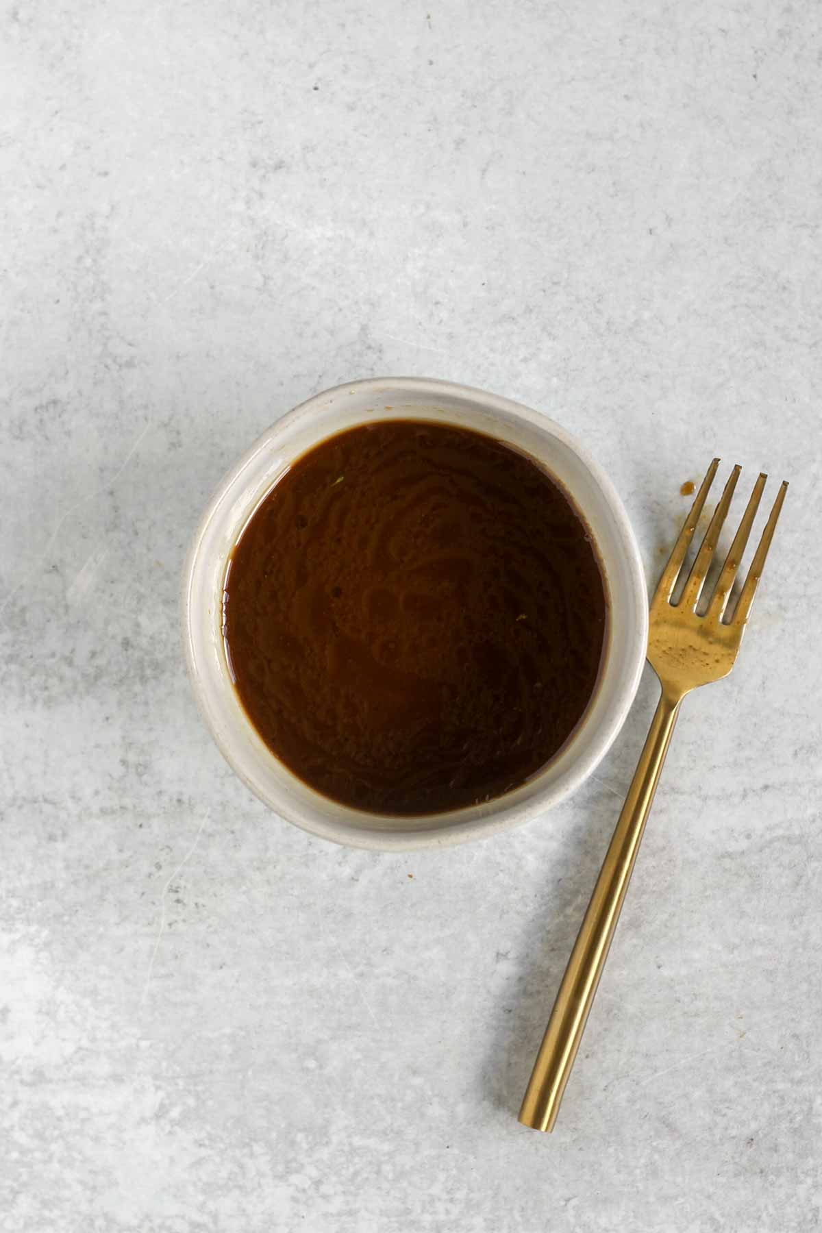 Stir fry sauce in s small bowl with a fork laying on the side.