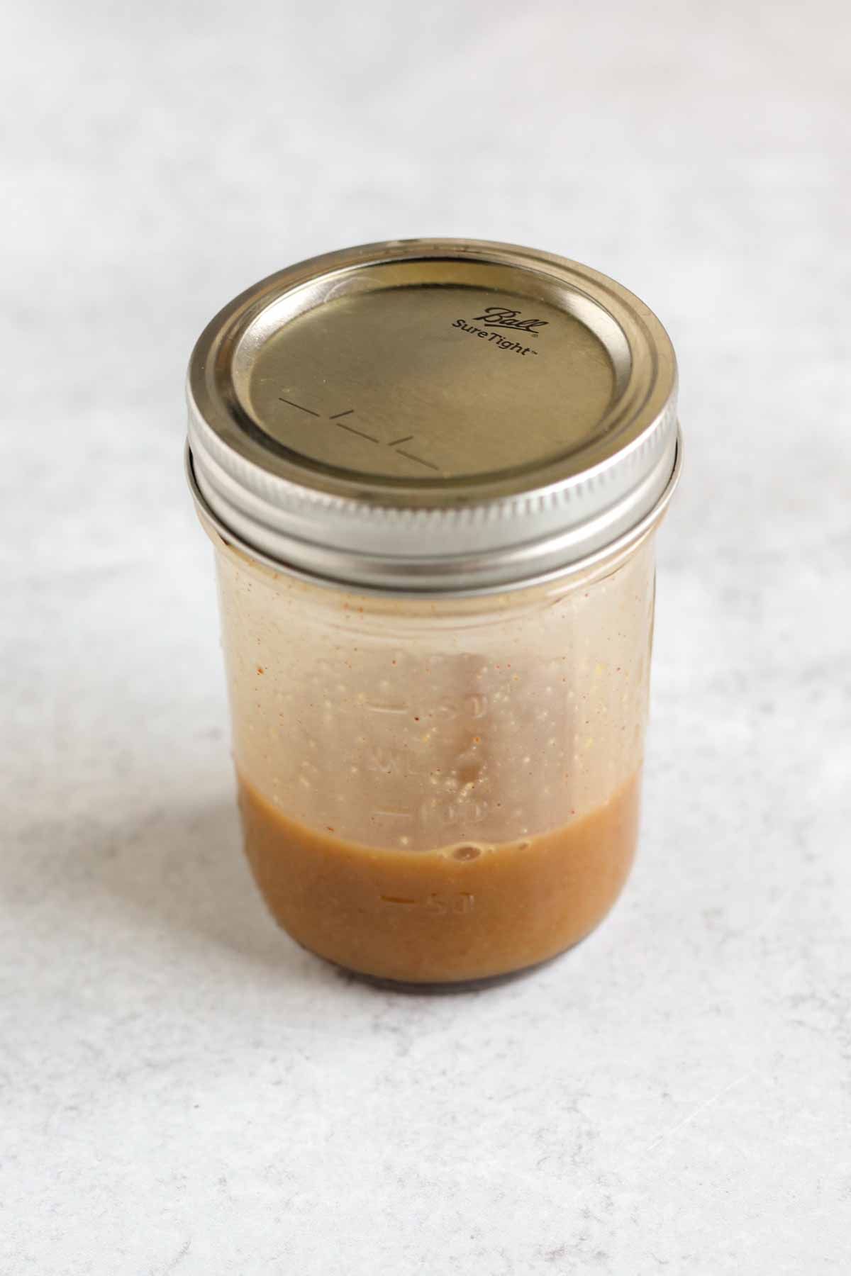 Covered mason jar with maple Dijon vinaigrette.