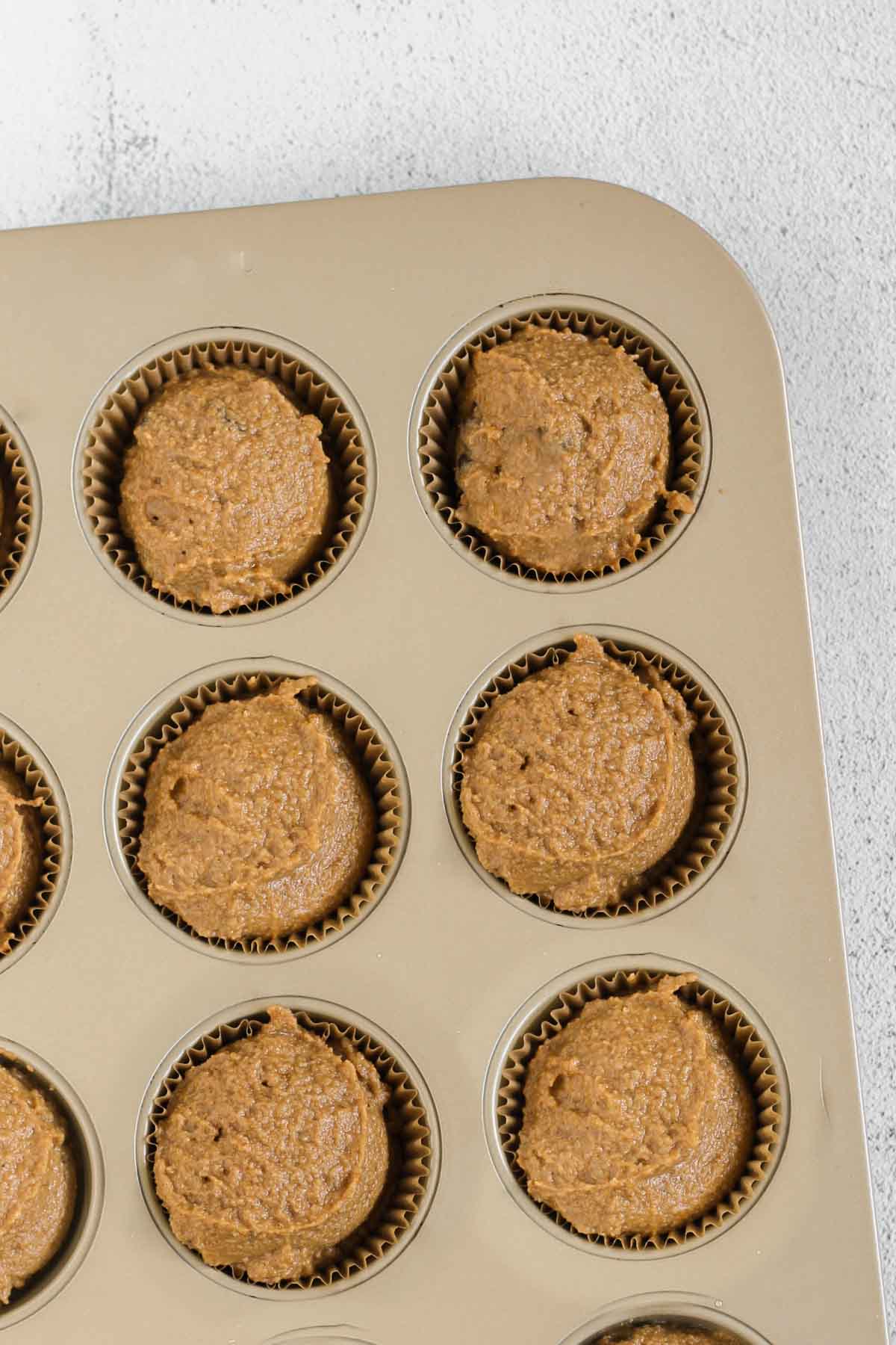 Almond flour pumpkin muffin batter in a muffin tin.