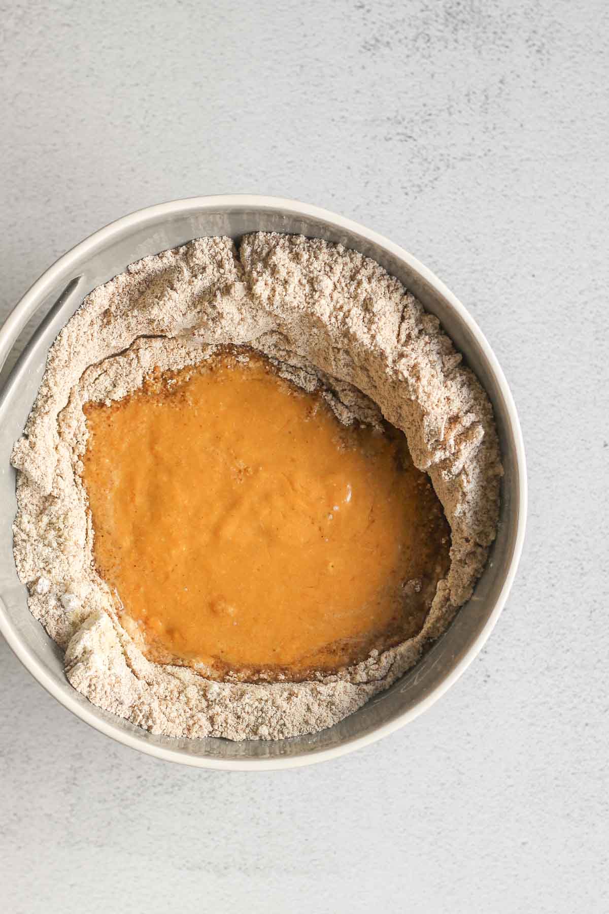 Dry ingredients, with we ingredients, for almond flour pumpkin muffins mixed in a gray mixing bowl.