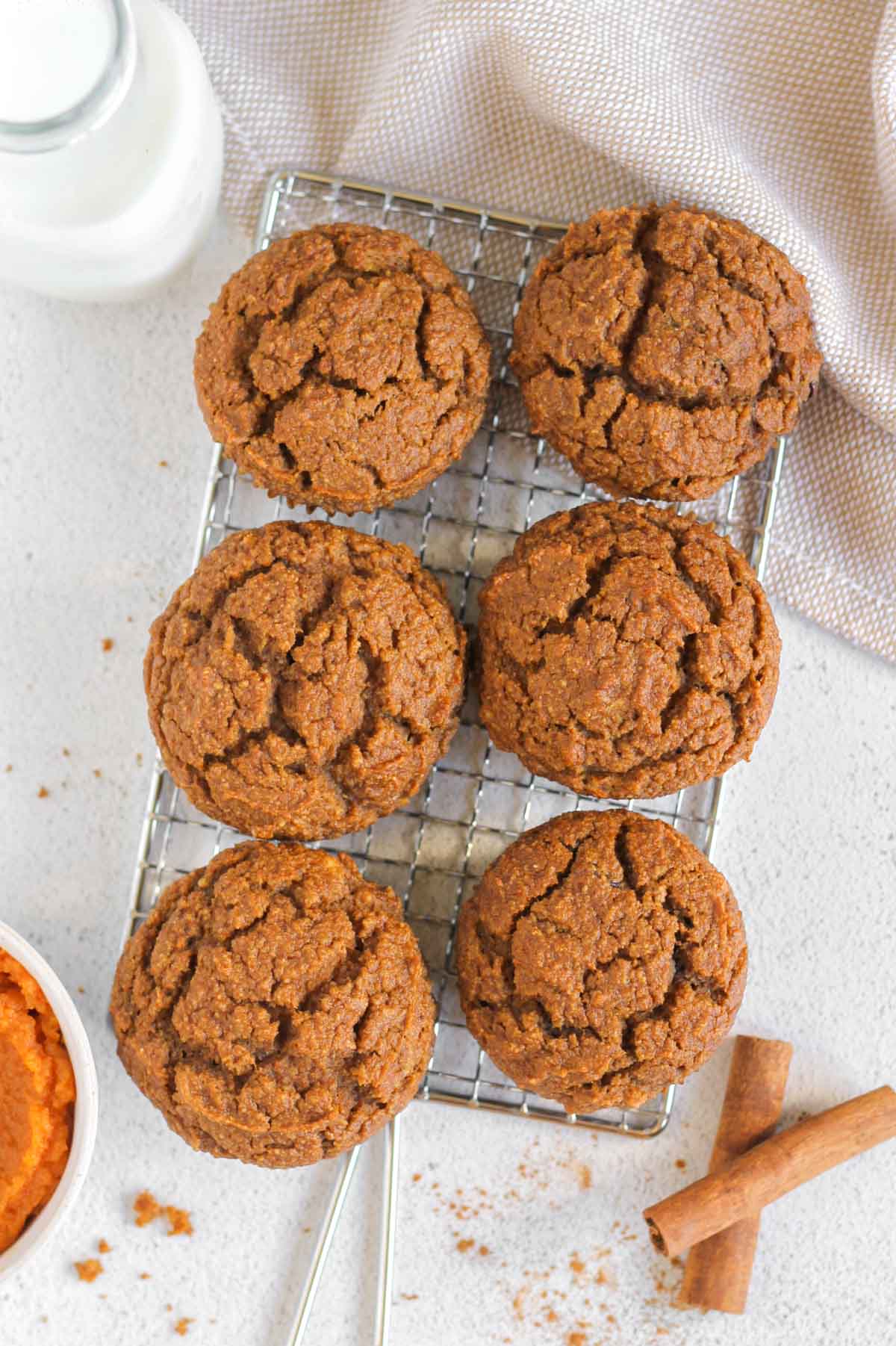 Six pumpkin muffins on a rectangular cooling rack.