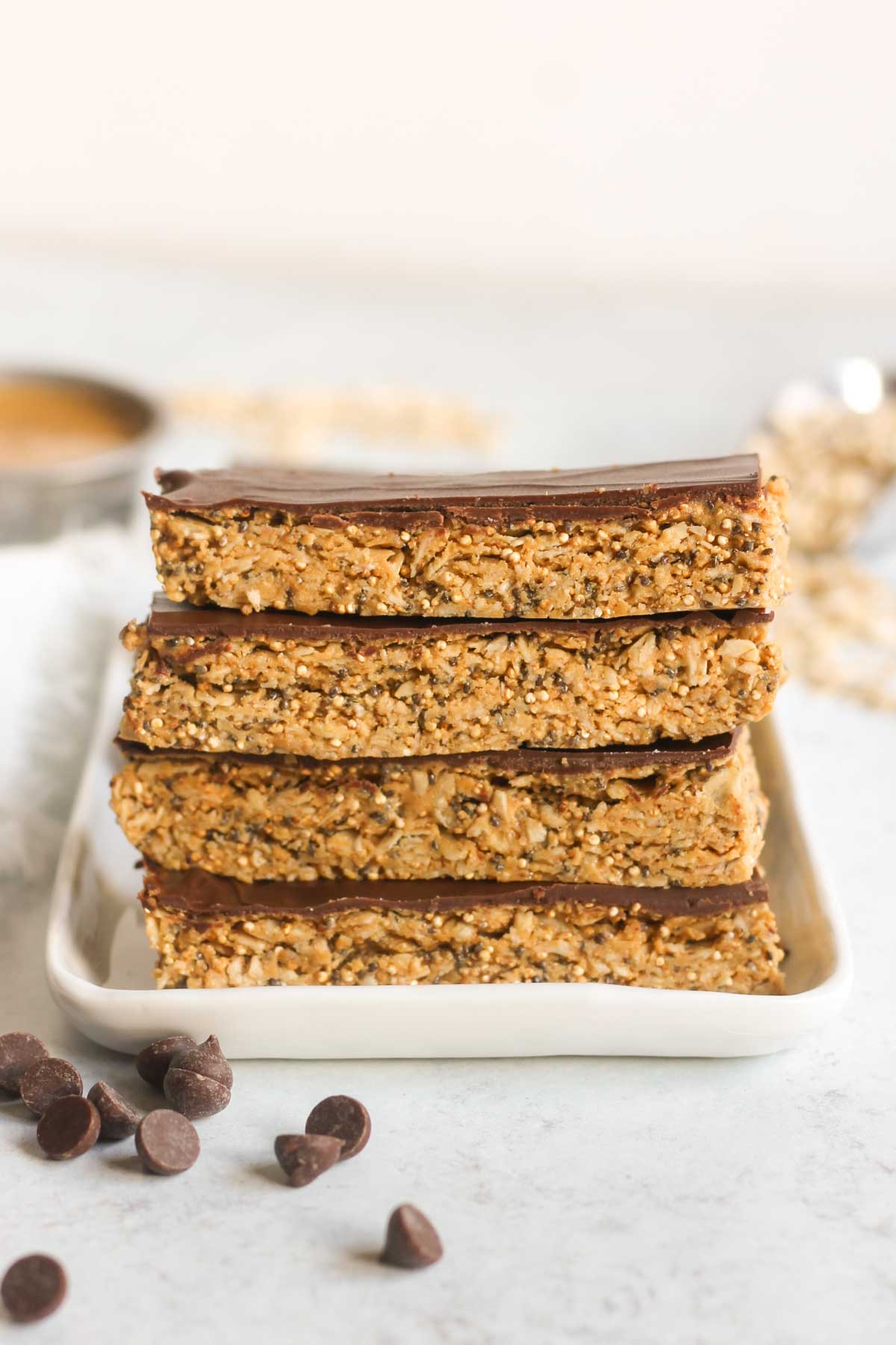 Four granola bars with chocolate topped stacked on top of one another.