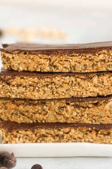 Four granola bars with chocolate topped stacked on top of one another.