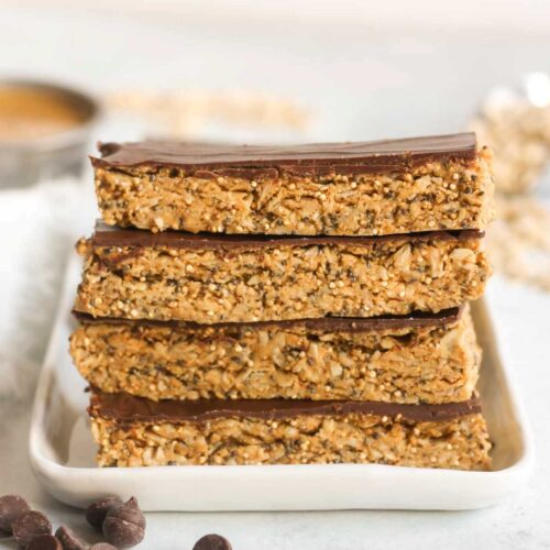 Four granola bars with chocolate topped stacked on top of one another.