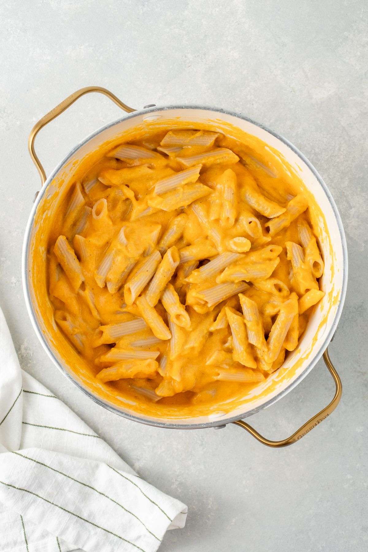 Penne noodles mixed with butternut squash cheese sauce in a large stock pot.
