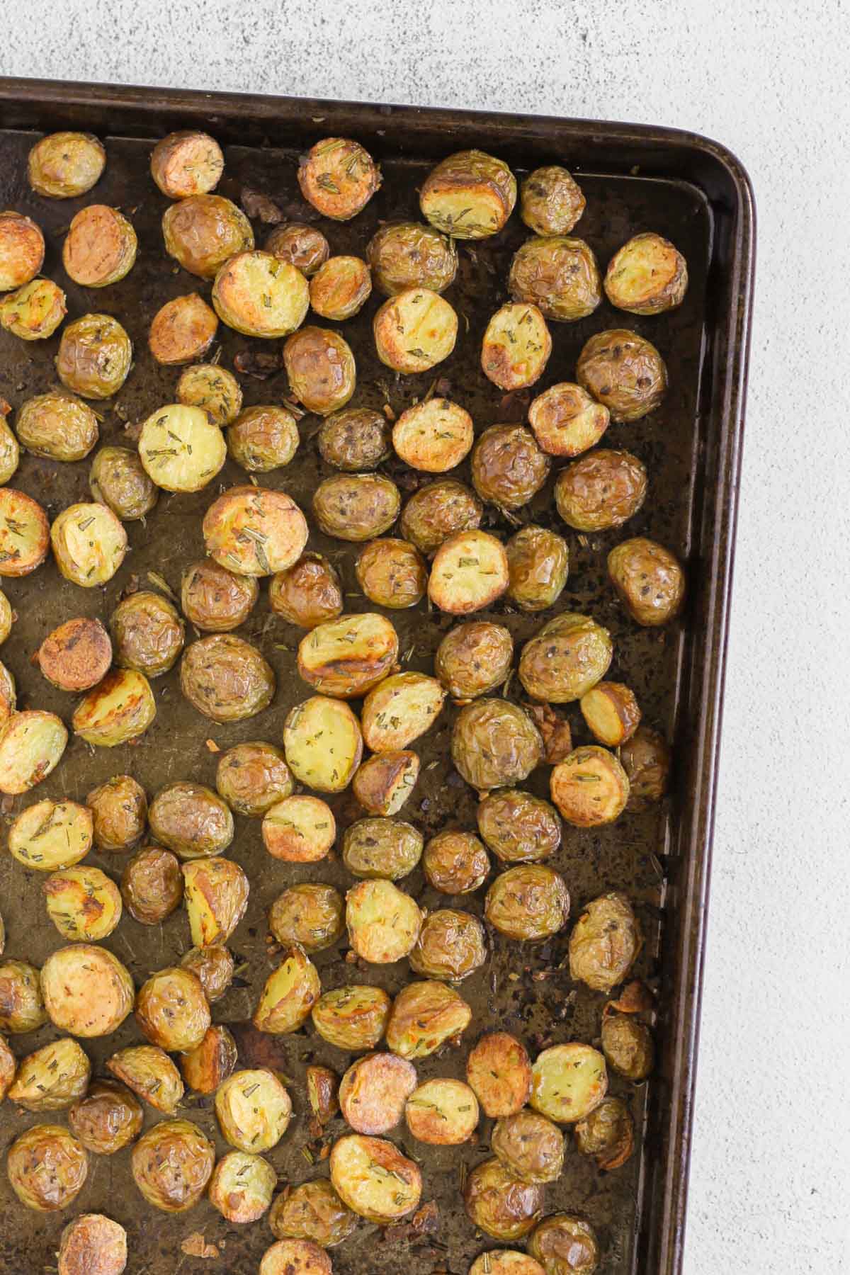 Roasted halved baby potatoes on a large baking sheet.