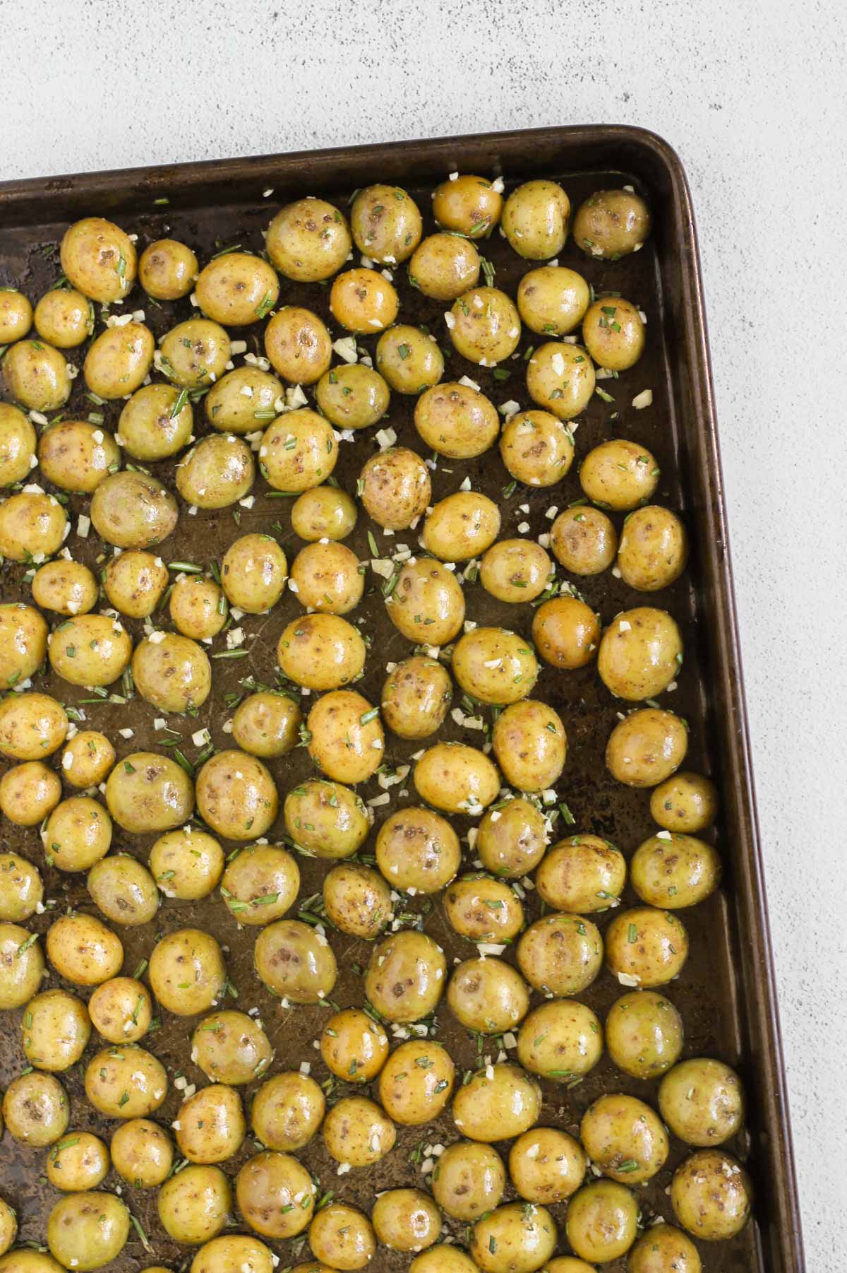 Sliced baby potatoes, cut side down, on a baking sheet before being baked.