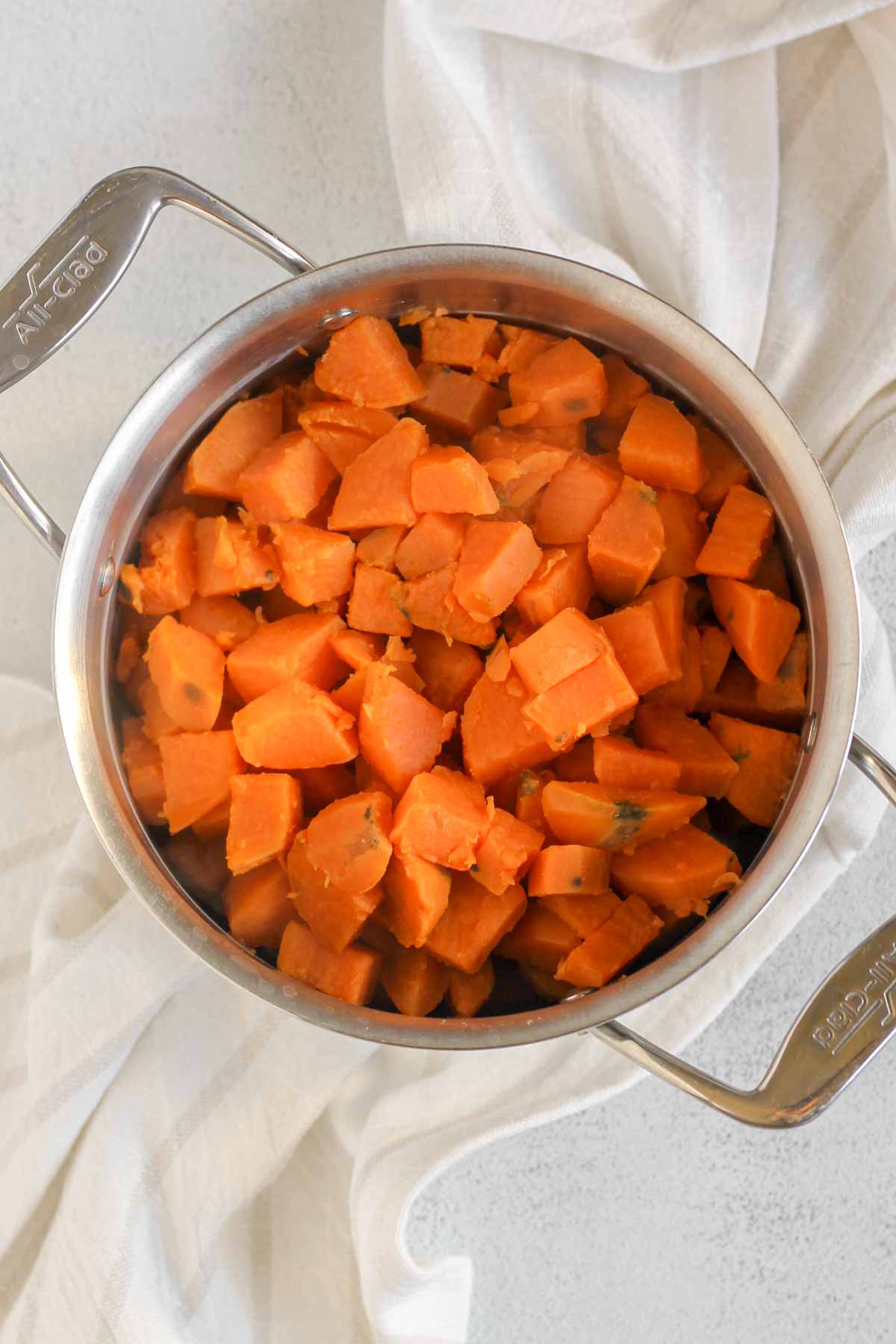Boiled sweet potato cubes in a stainless steel pot.