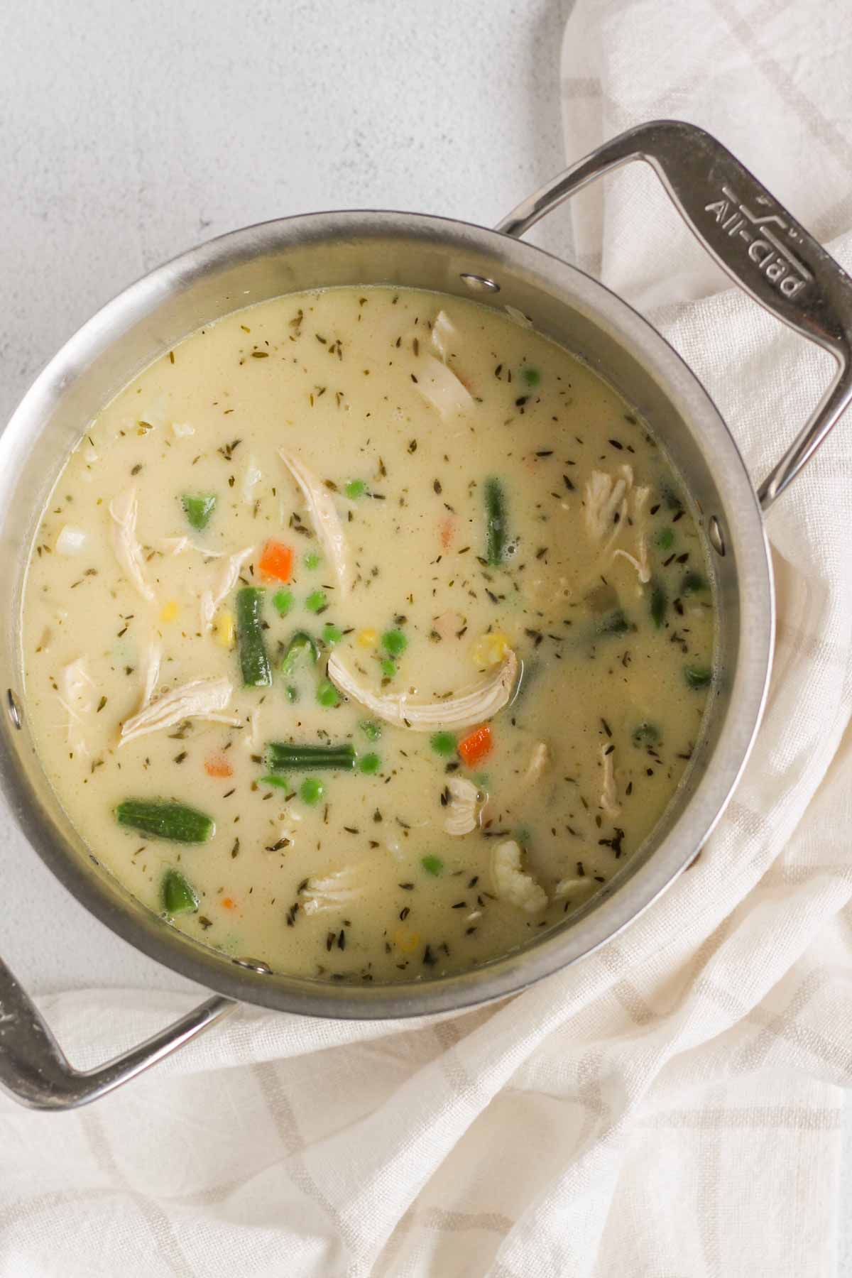 Creamy chicken pot pie soup cooking in a stainless steel stock pot.