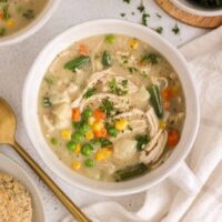 Bowl of creamy chicken pot pie soup with a gold spoon on the side.