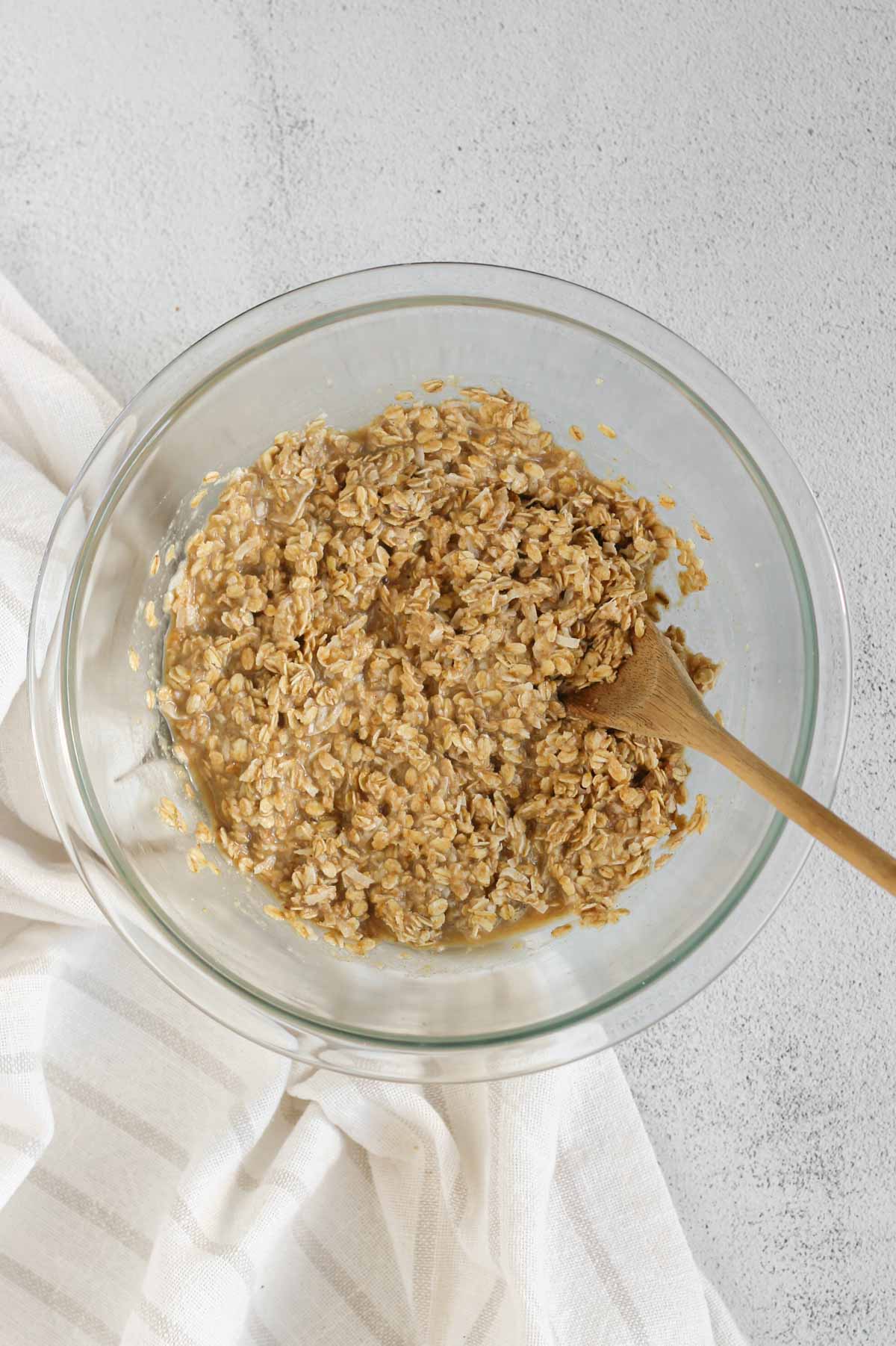 Breakfast cookie mix base in a glass mixing bowl with a wooden spoon.