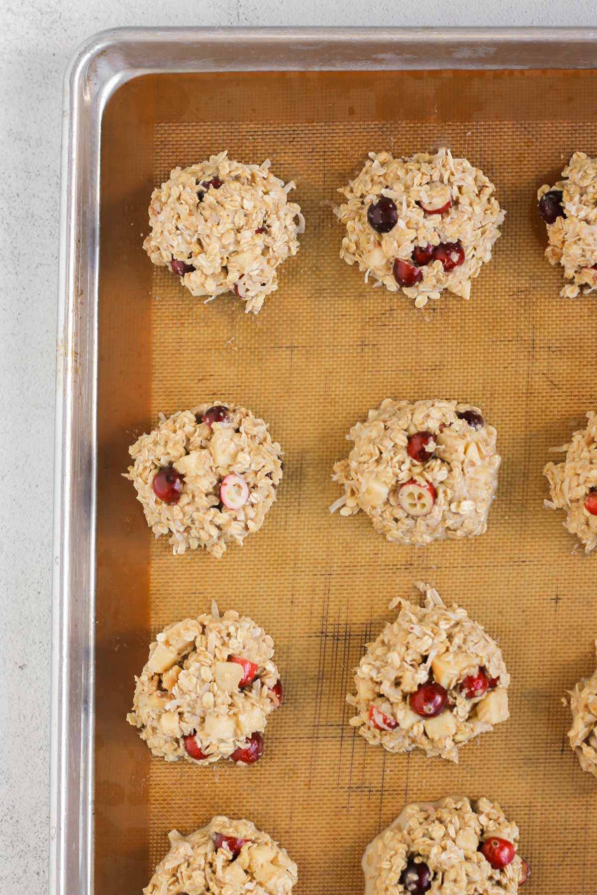 Cranberry apple breakfast cookies unbaked dough on a cookie sheet lined with a silicone baking mat.