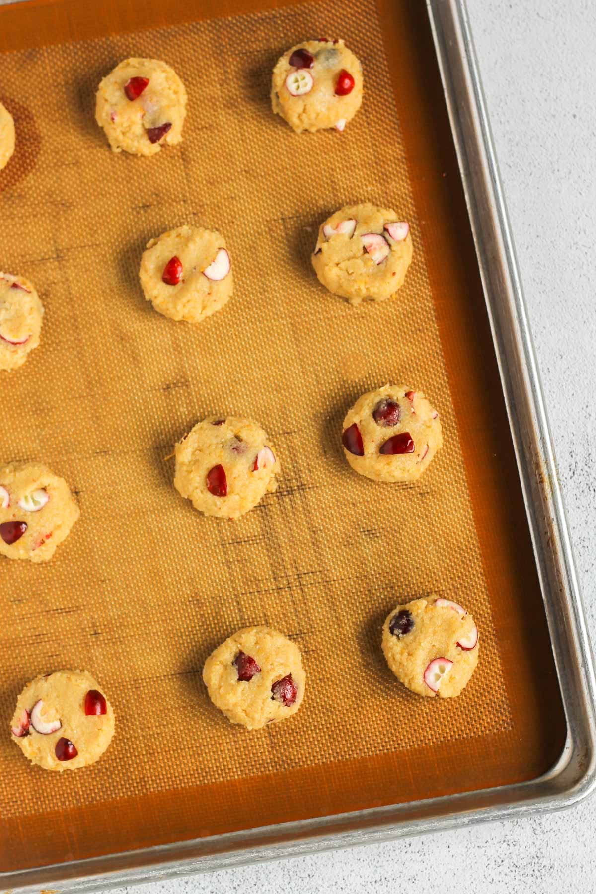 Almond flour cranberry cookie dough balls on a baking sheet before being baked.