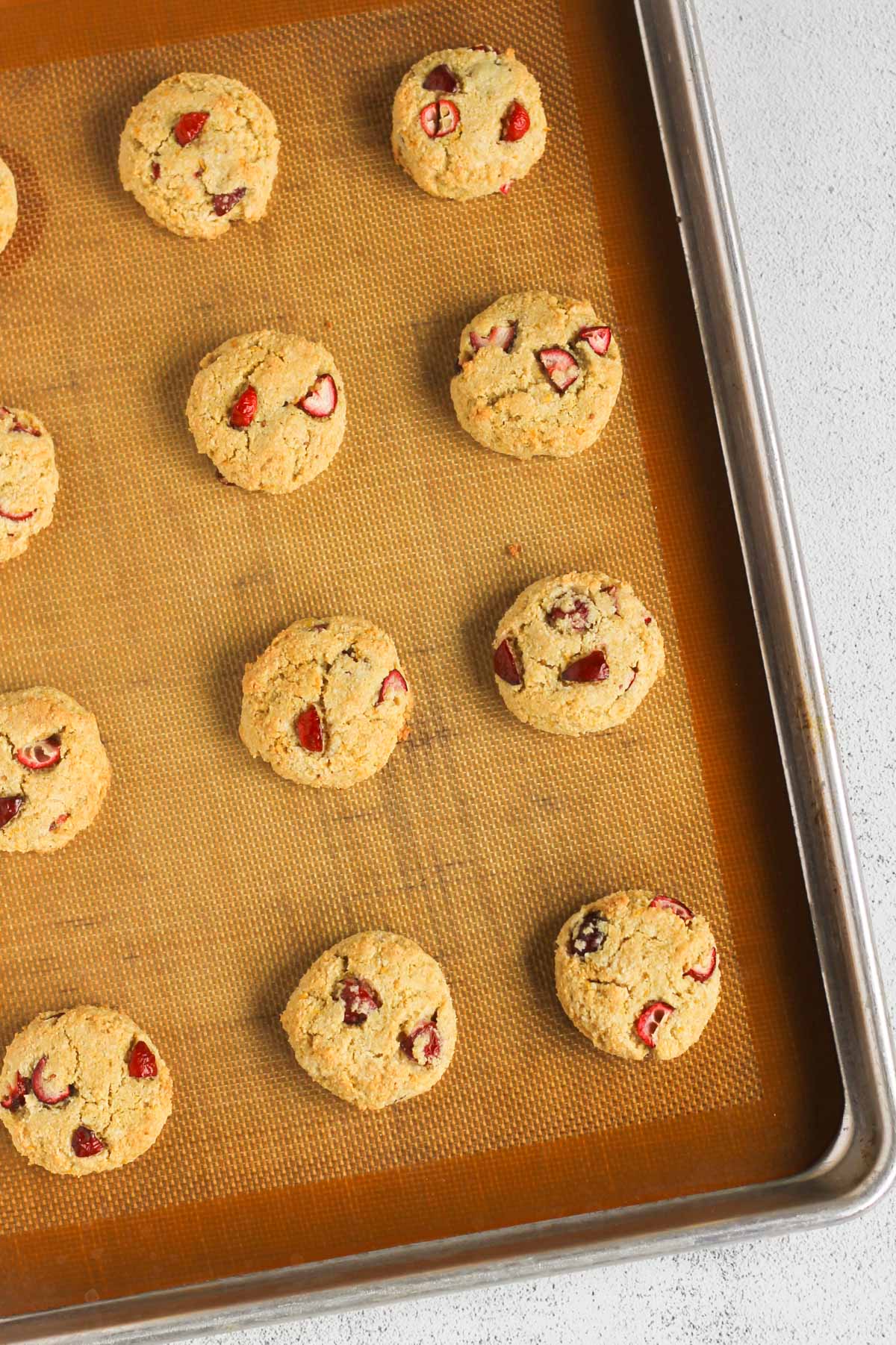 Cranberry almond flour cookies baked on a baking sheet with a silicone baking mat.